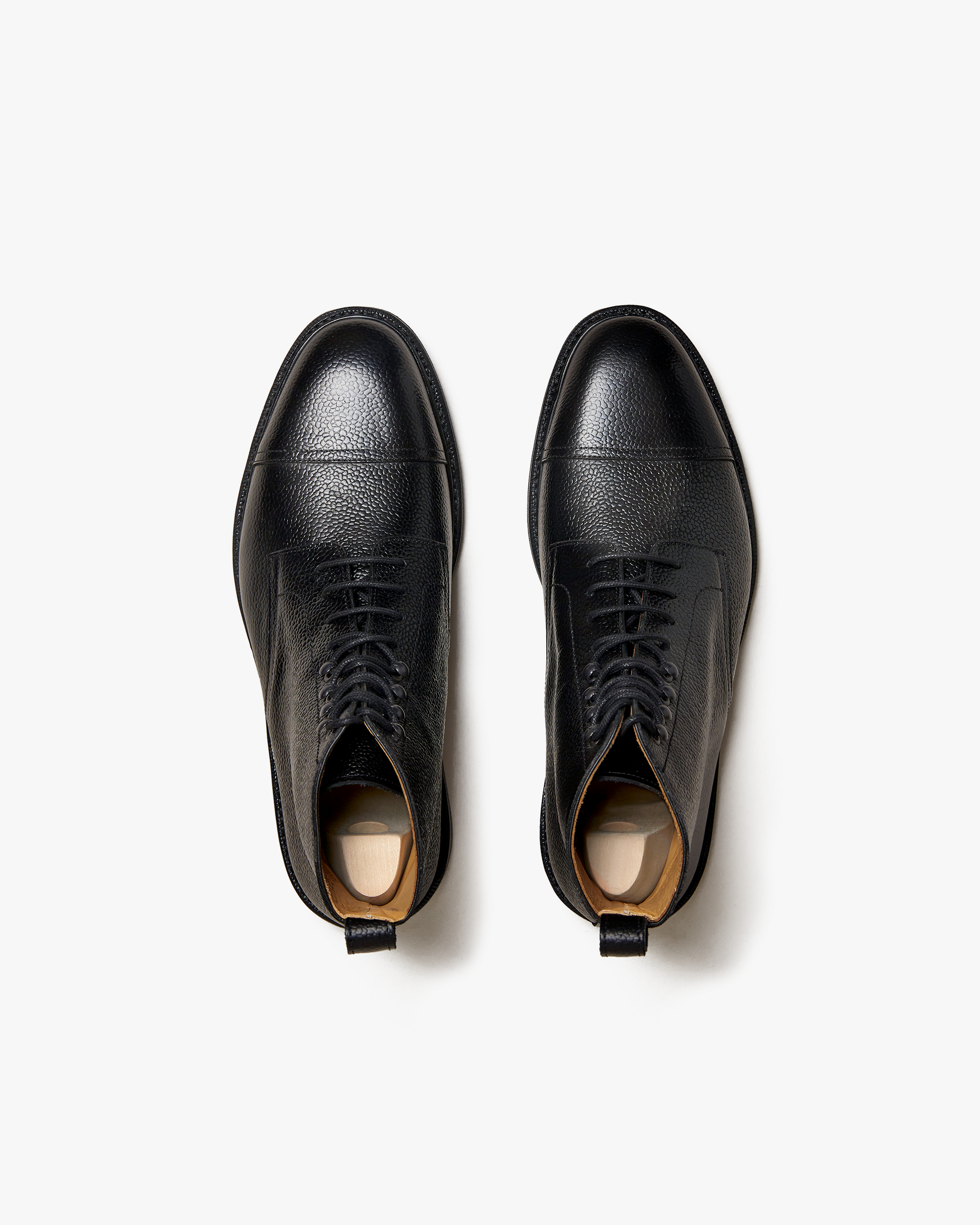 A top-down view of Abisko – Black Country Calf boots on a white background, highlighting their grained leather texture.