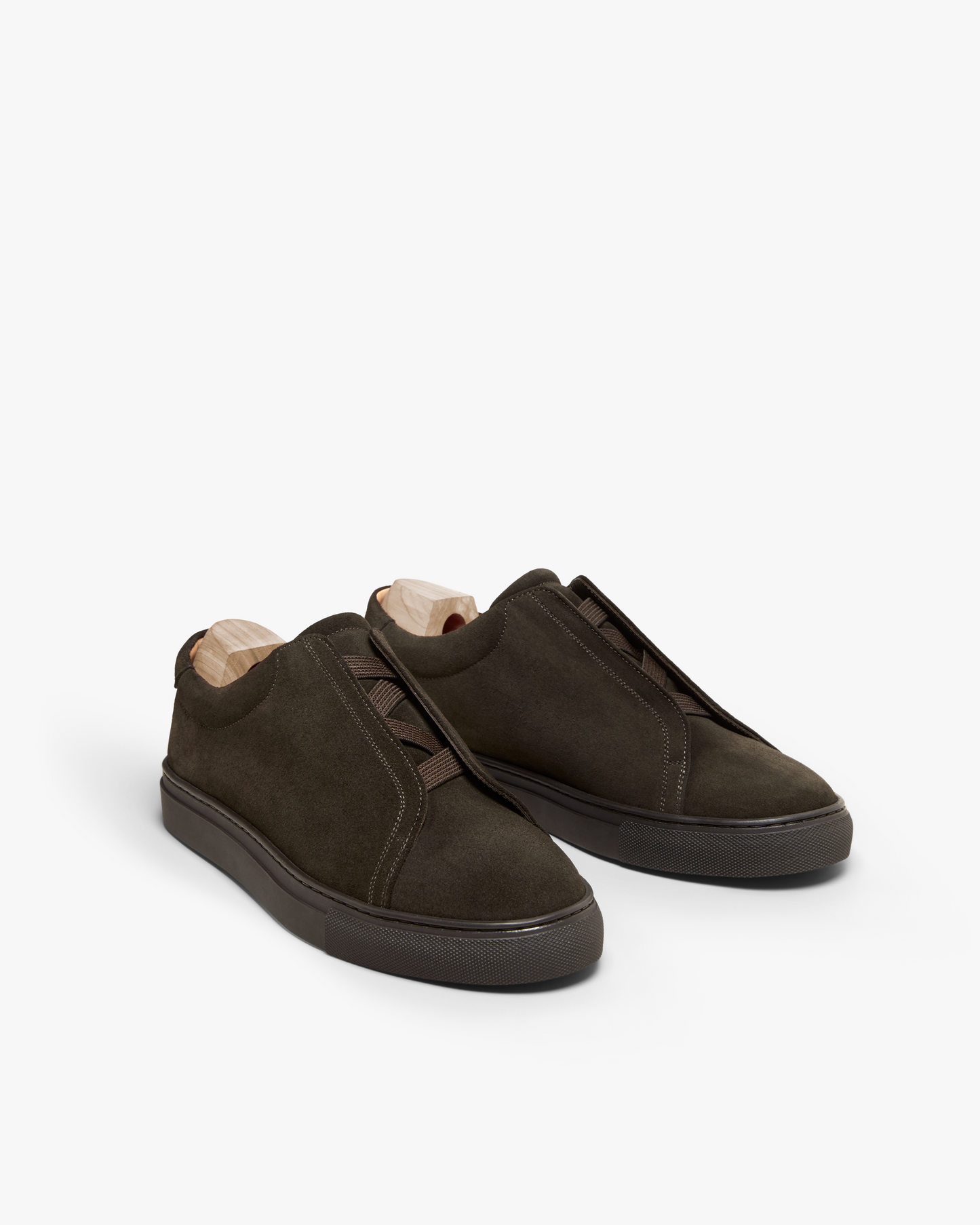 A pair of Alnö – Dark Brown Suede sneakers with shoe trees, photographed against a white studio background.