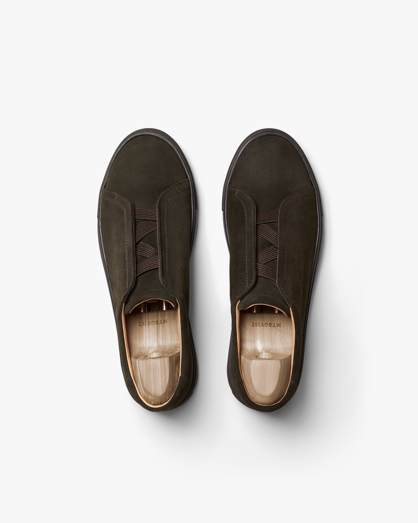 A pair of Alnö – Dark Brown Suede sneakers with shoe trees inside, photographed from above against a white background.