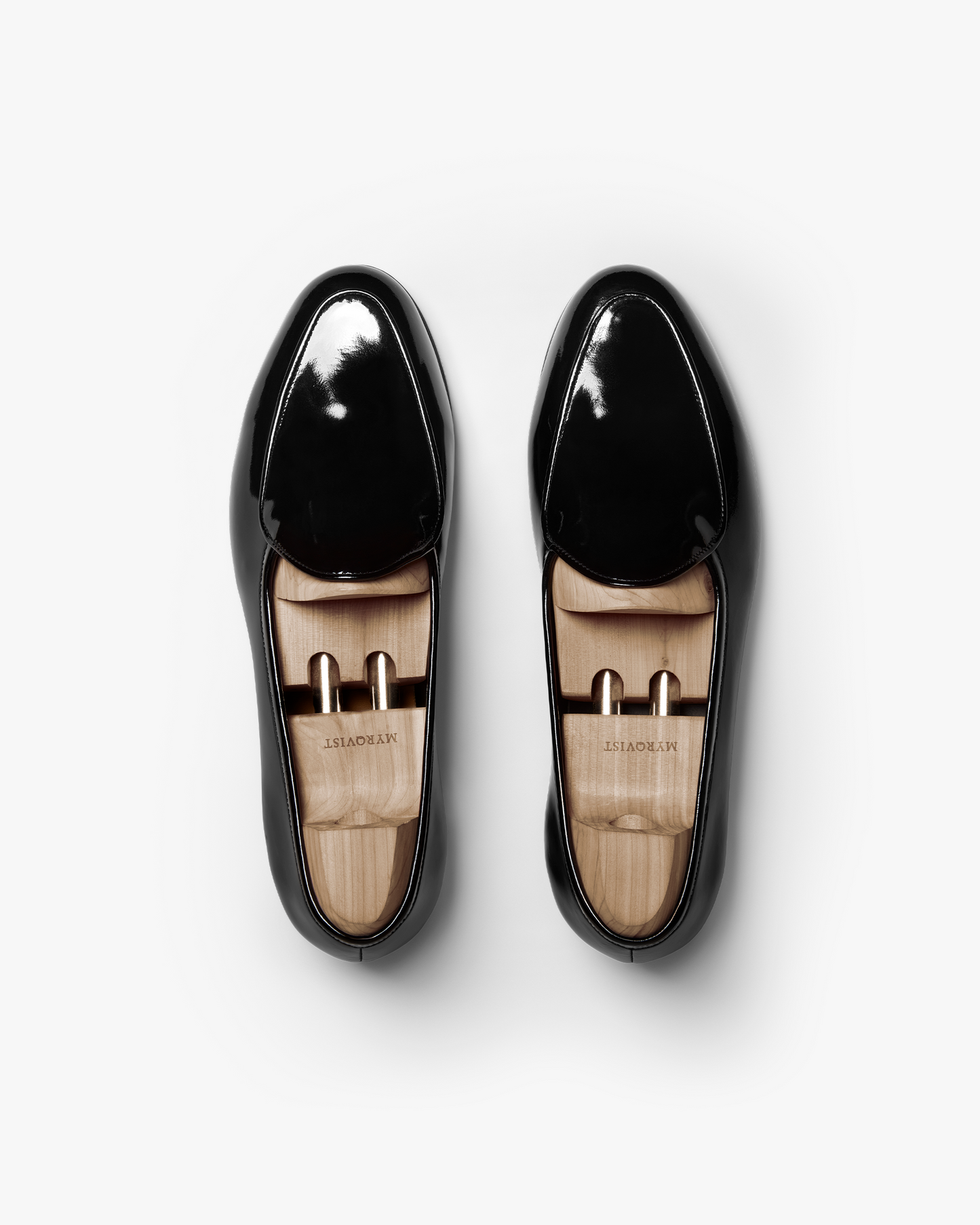 Overhead view of a pair of Ängby – Black Patent Leather loafers with wooden shoe trees on a white background.