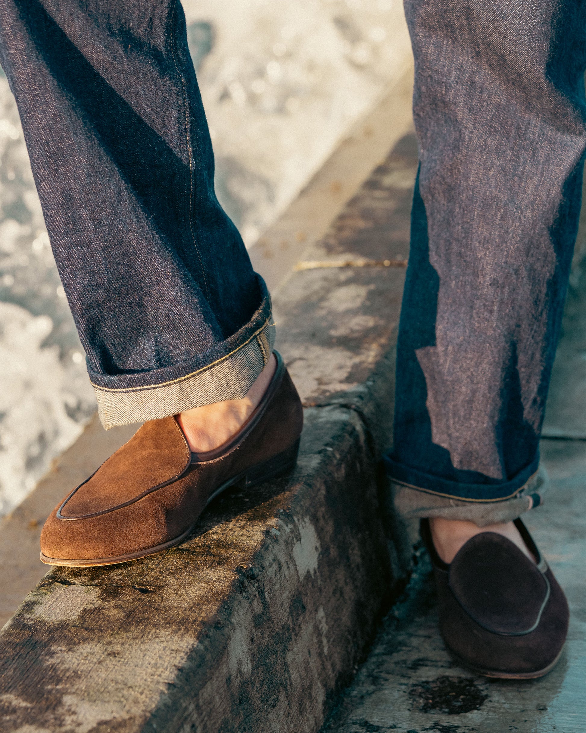 Close-up of a person wearing Ängby – Dark Brown Suede loafers with rolled-up dark jeans.