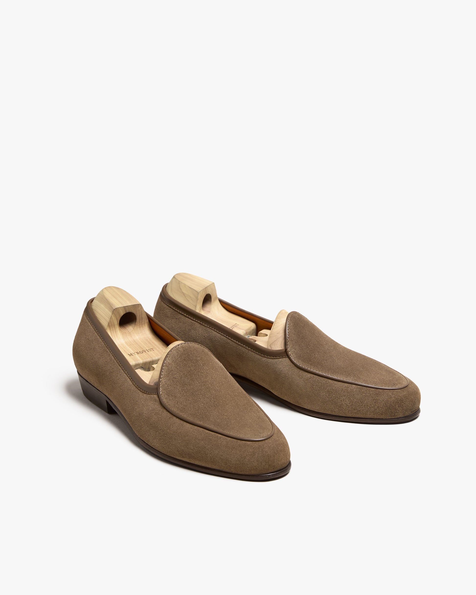 A studio shot of the Ängby – Taupe Suede loafers with wooden shoe trees inside, against a white background.