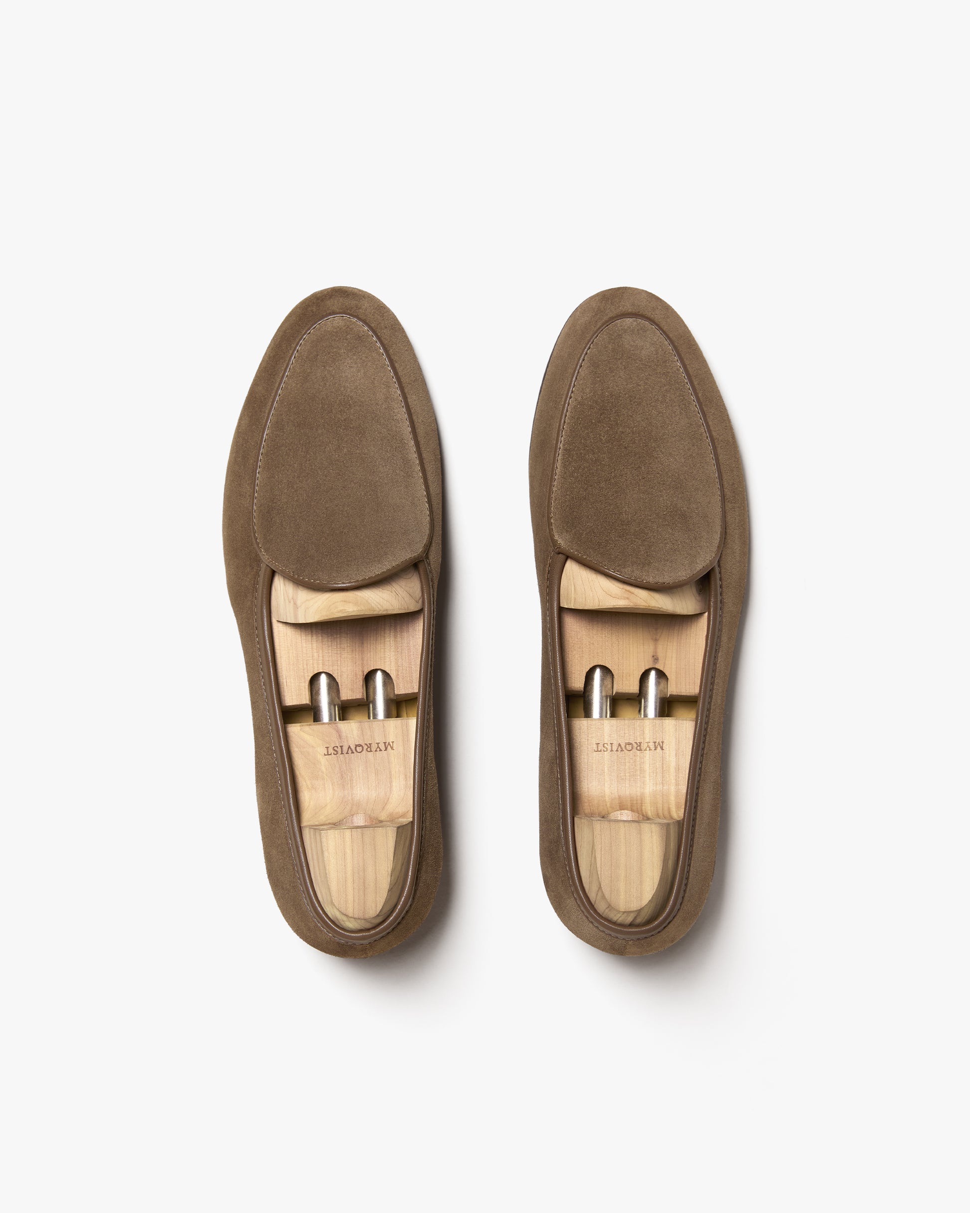 A pair of Ängby – Taupe Suede loafers with wooden shoe trees, shot from above against a white background.