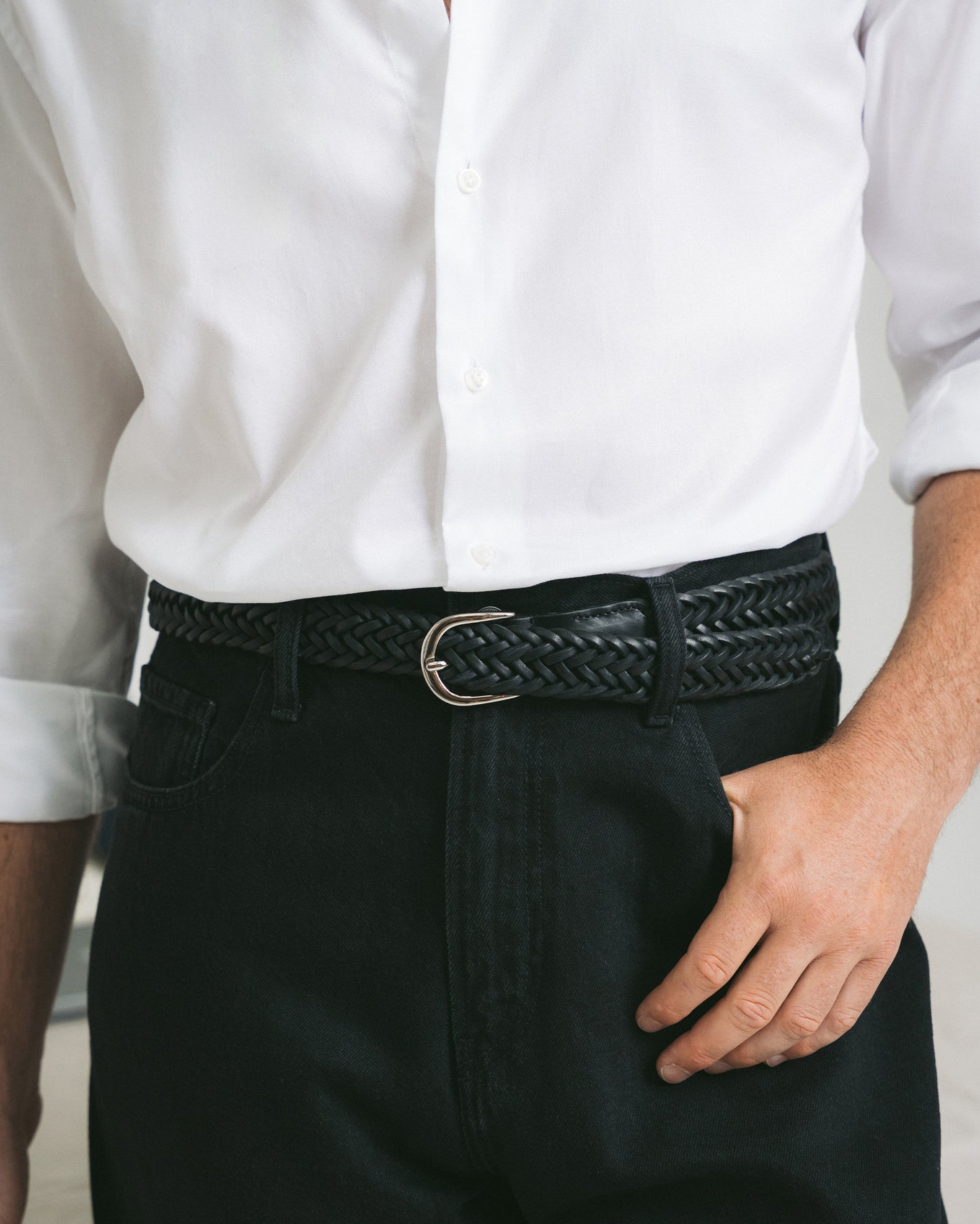 Close-up of a person wearing Belt – Braided Black Leather with a white shirt and black trousers.