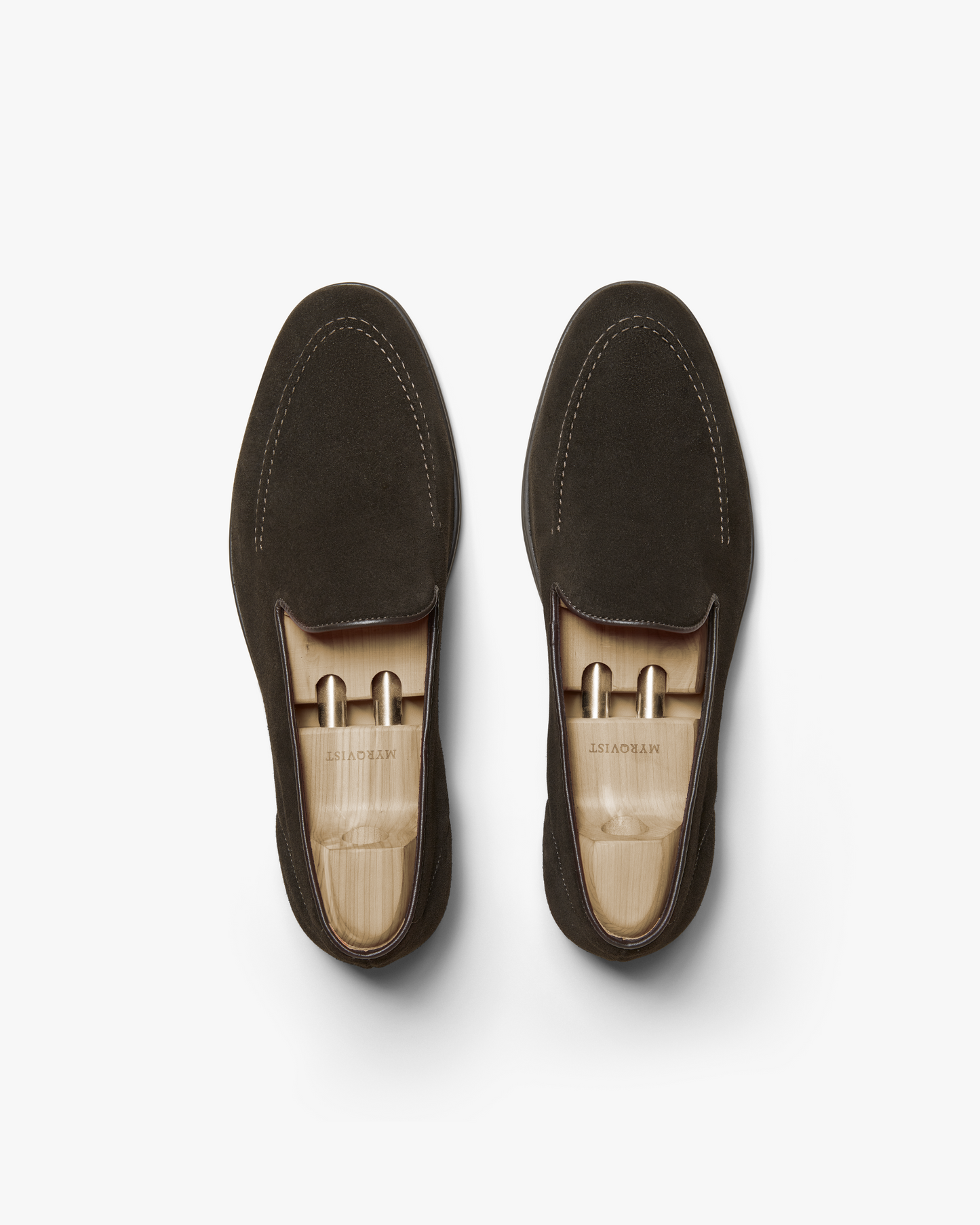 A pair of Brännö II – Dark Brown Suede loafers with wooden shoe trees, photographed from above on a white background.