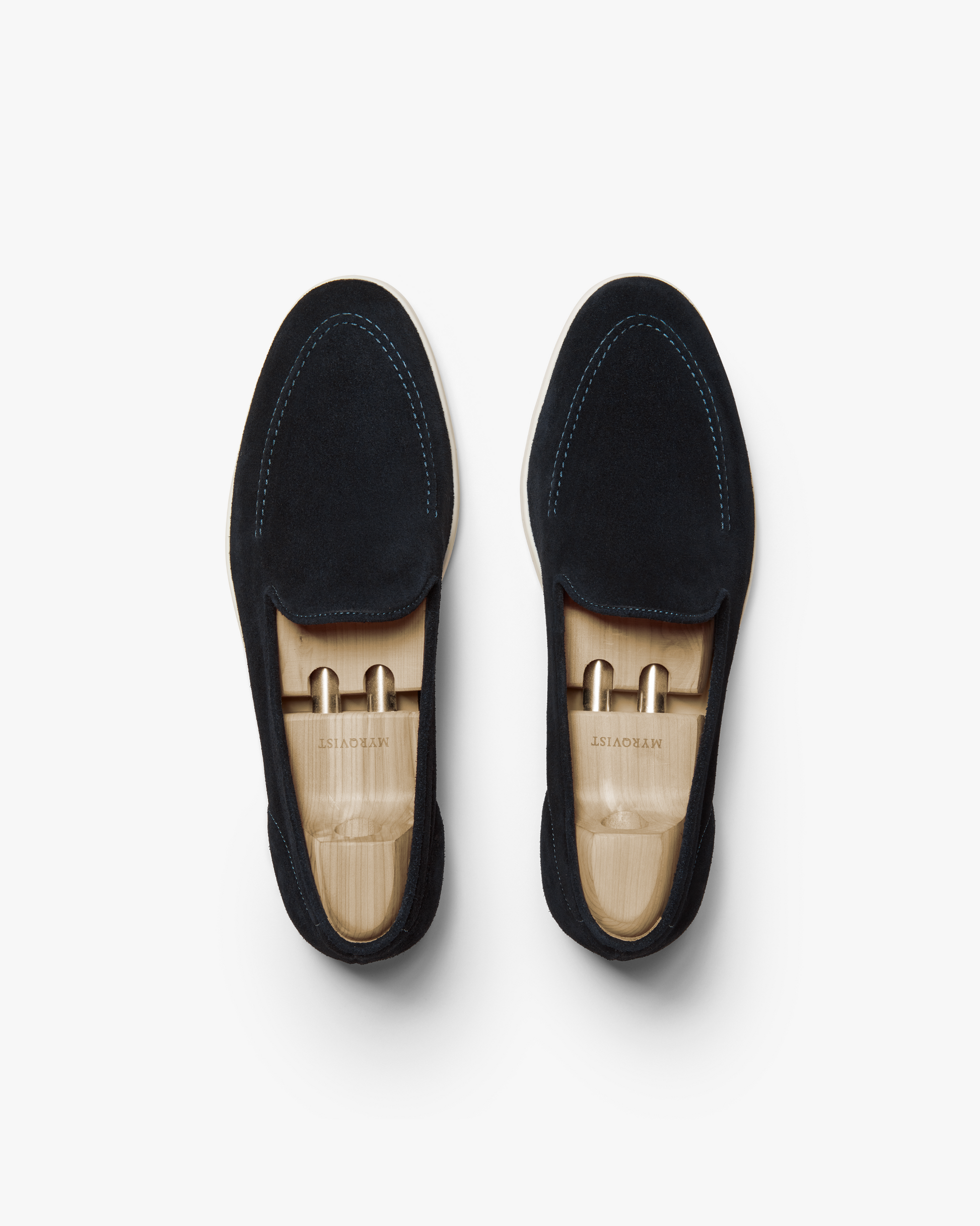 A top-down shot of a pair of Brännö II – Navy Suede loafers fitted with wooden shoe trees.