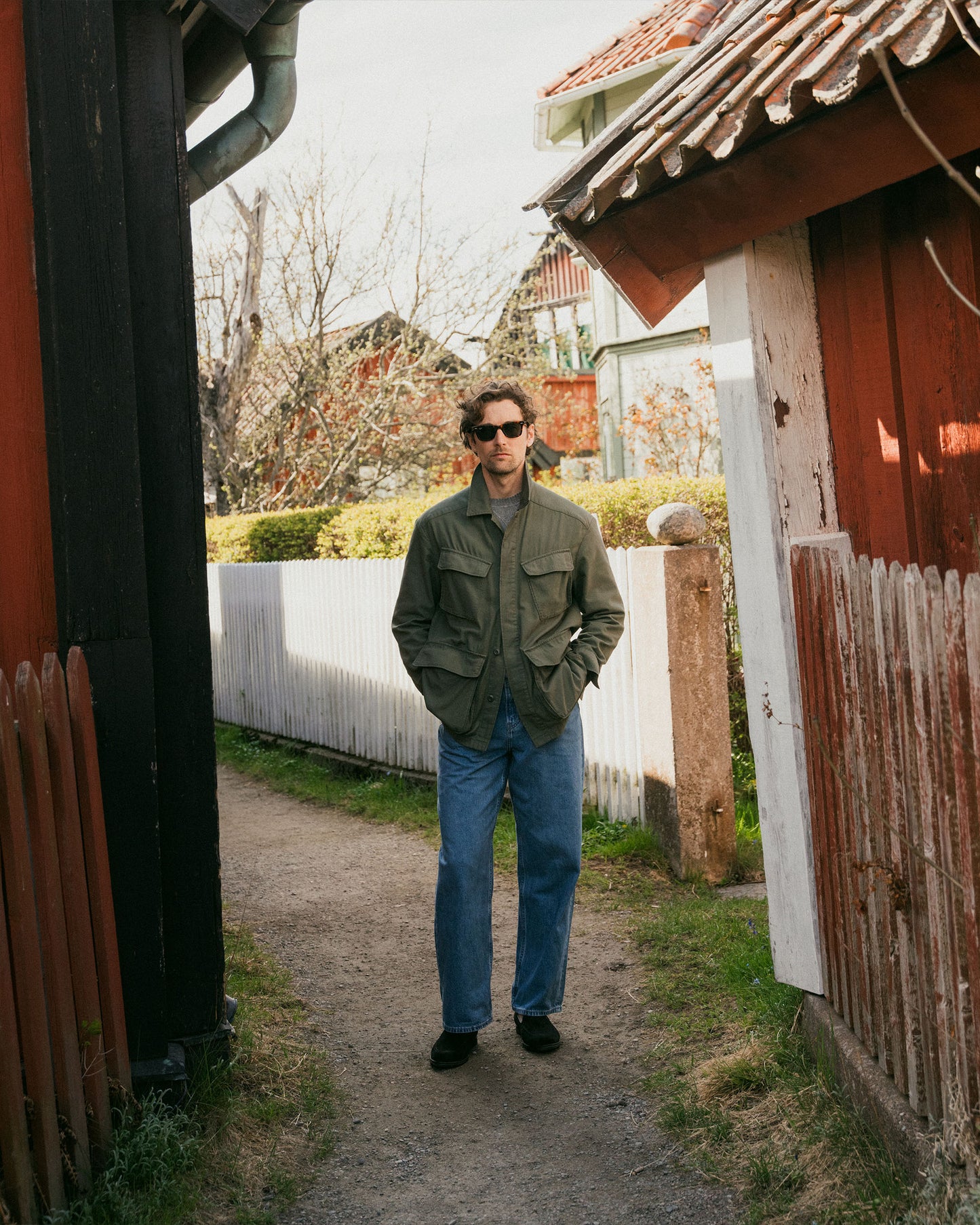 Full look of a man wearing Brännö II – Black Suede loafers with blue jeans and a green utility jacket.