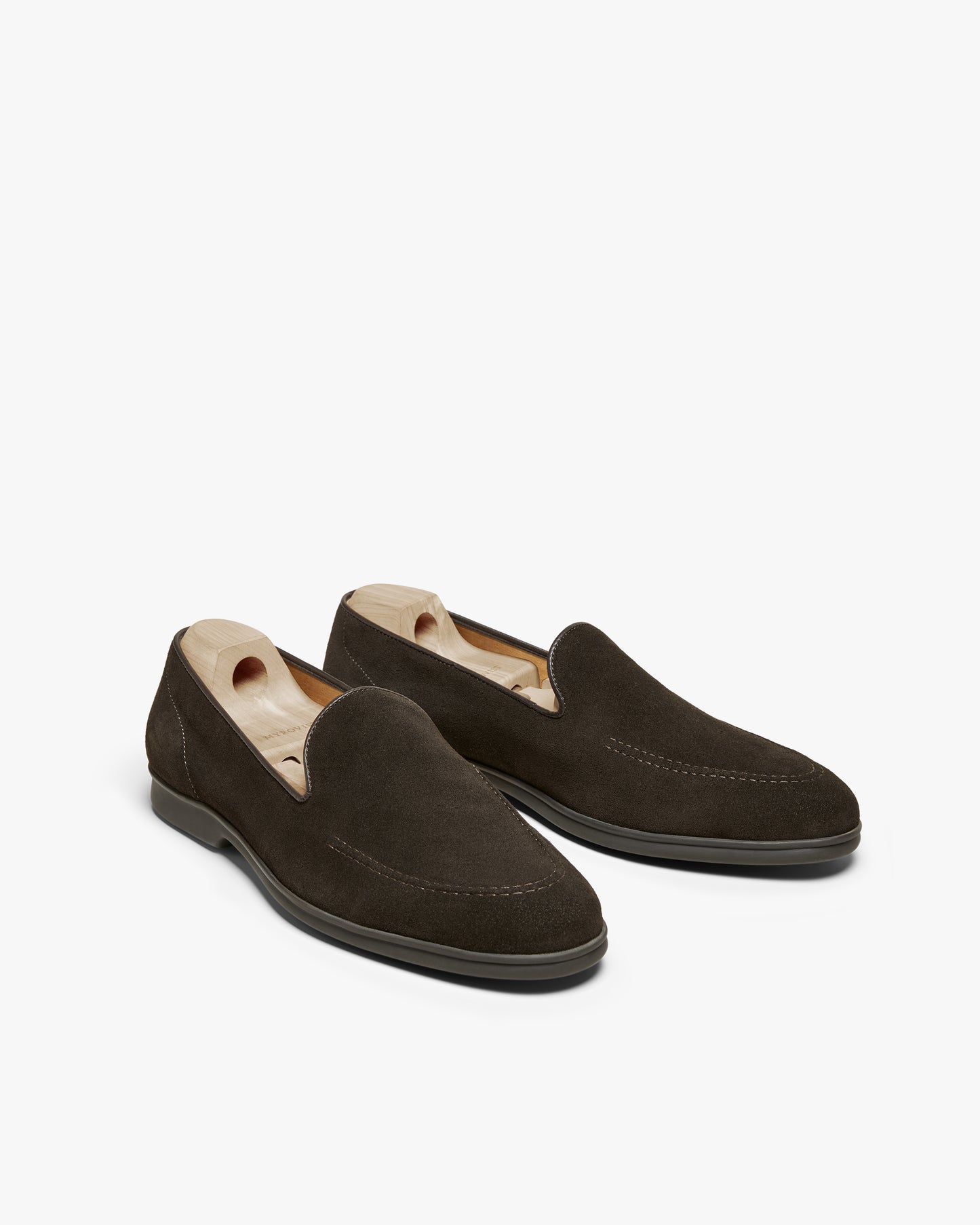 A pair of Brännö II – Dark Brown Suede loafers with shoe trees against a white background.