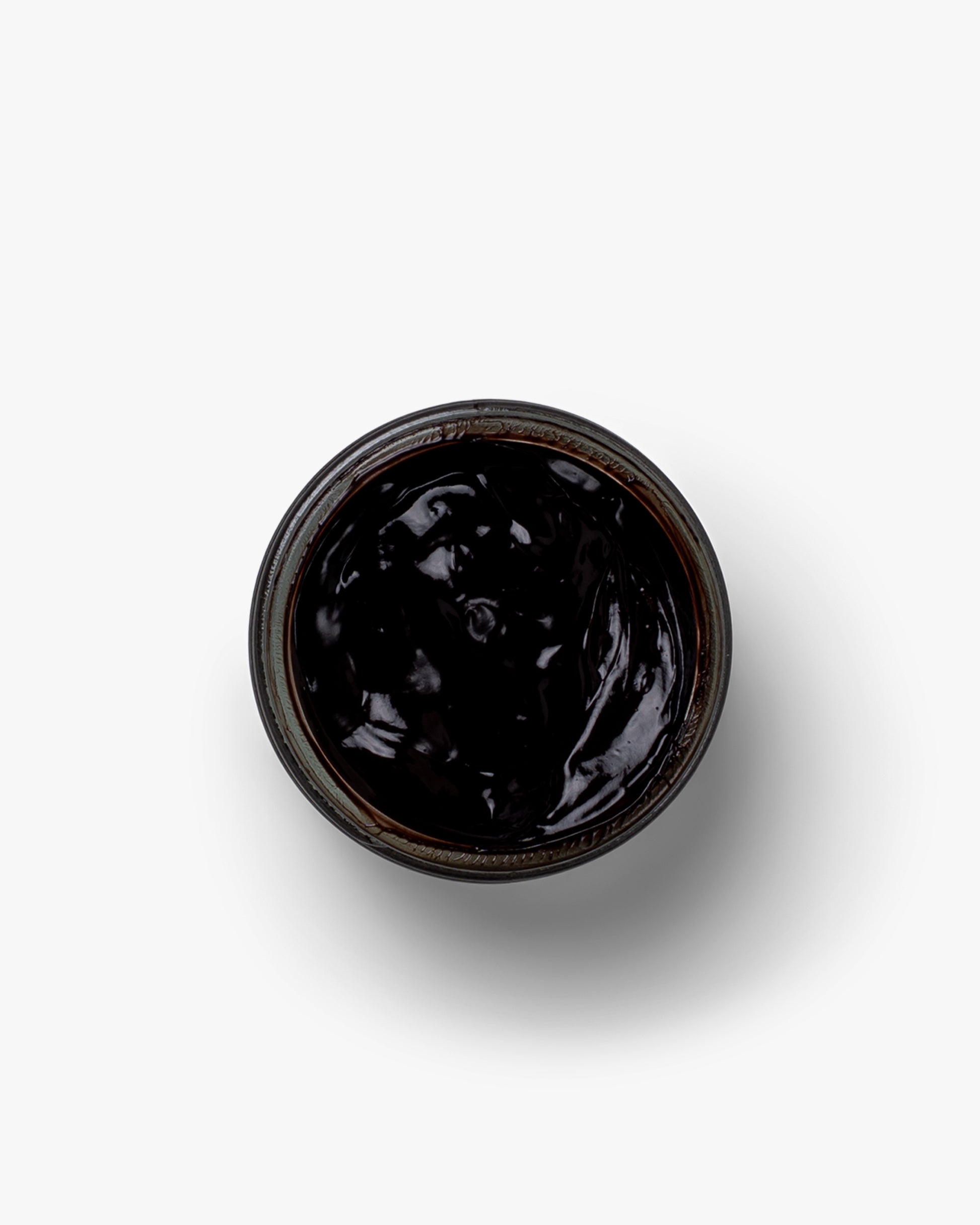 A top-down view of an open jar of Myrqvist brown shoe cream, highlighting its rich and glossy texture.