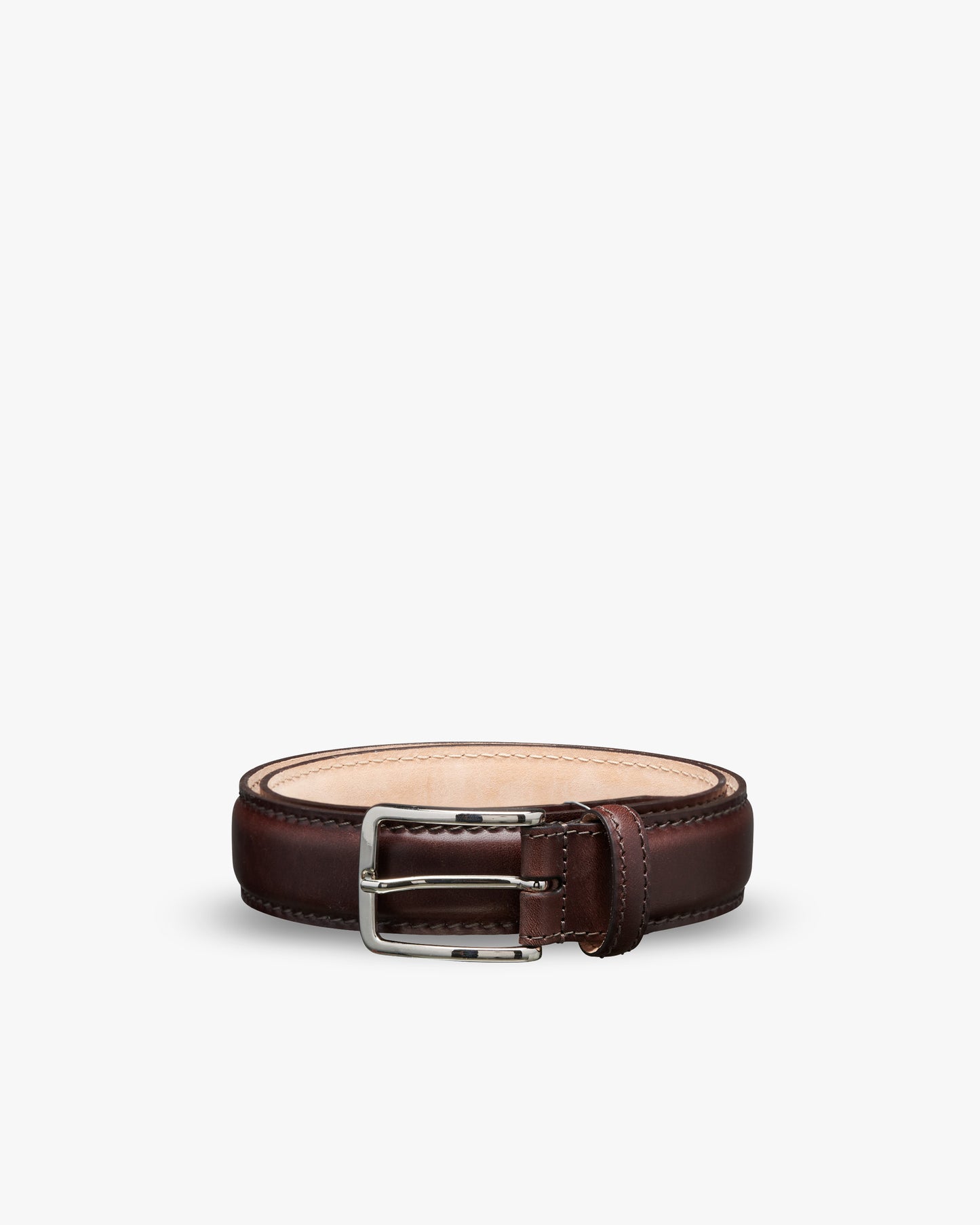 A close-up of the Belt – Dark Brown Leather, coiled to display its square silver-colored buckle.