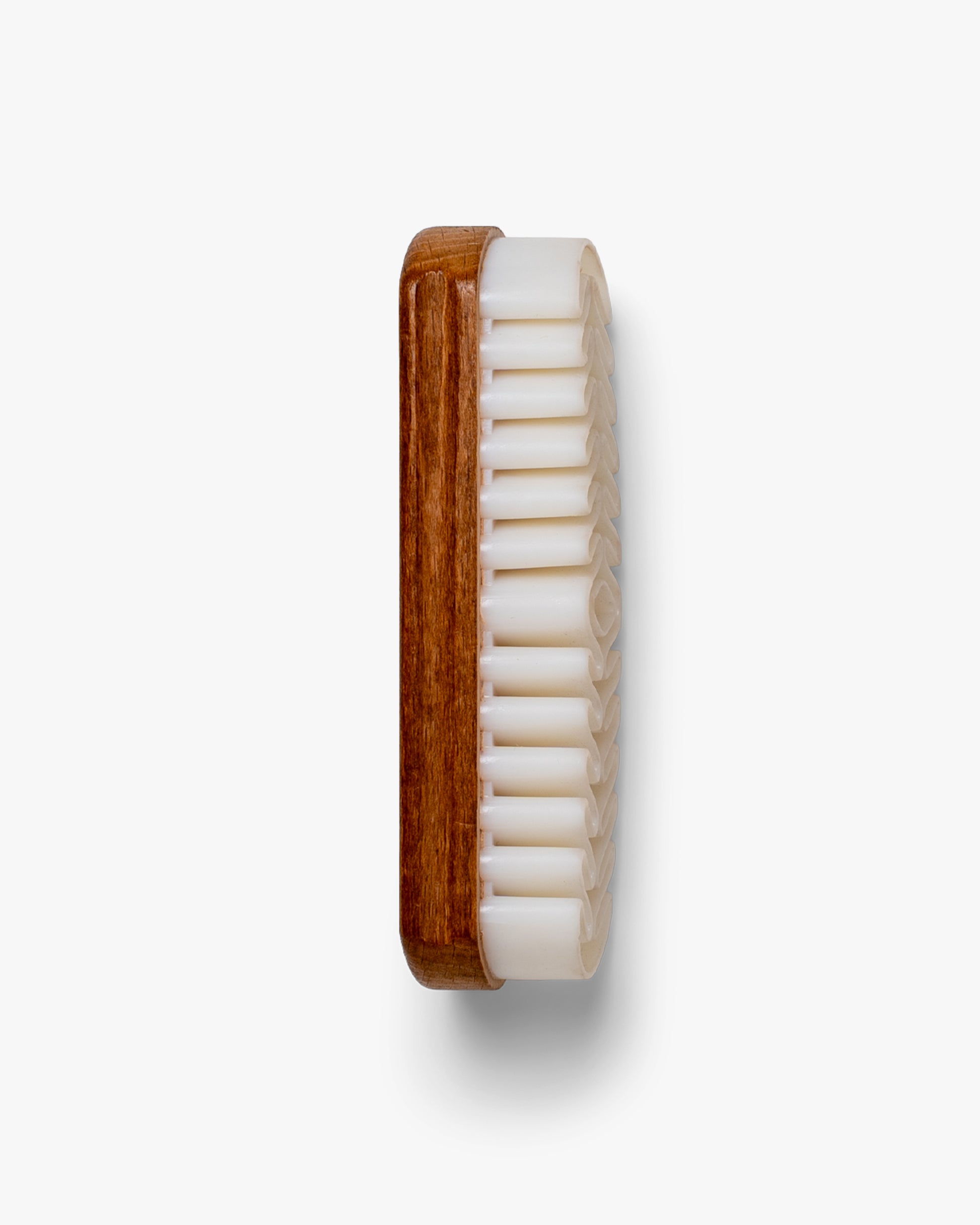 A top-down studio shot of the Suede Brush – Crepe, detailing its wooden handle and textured crepe rubber bristles.