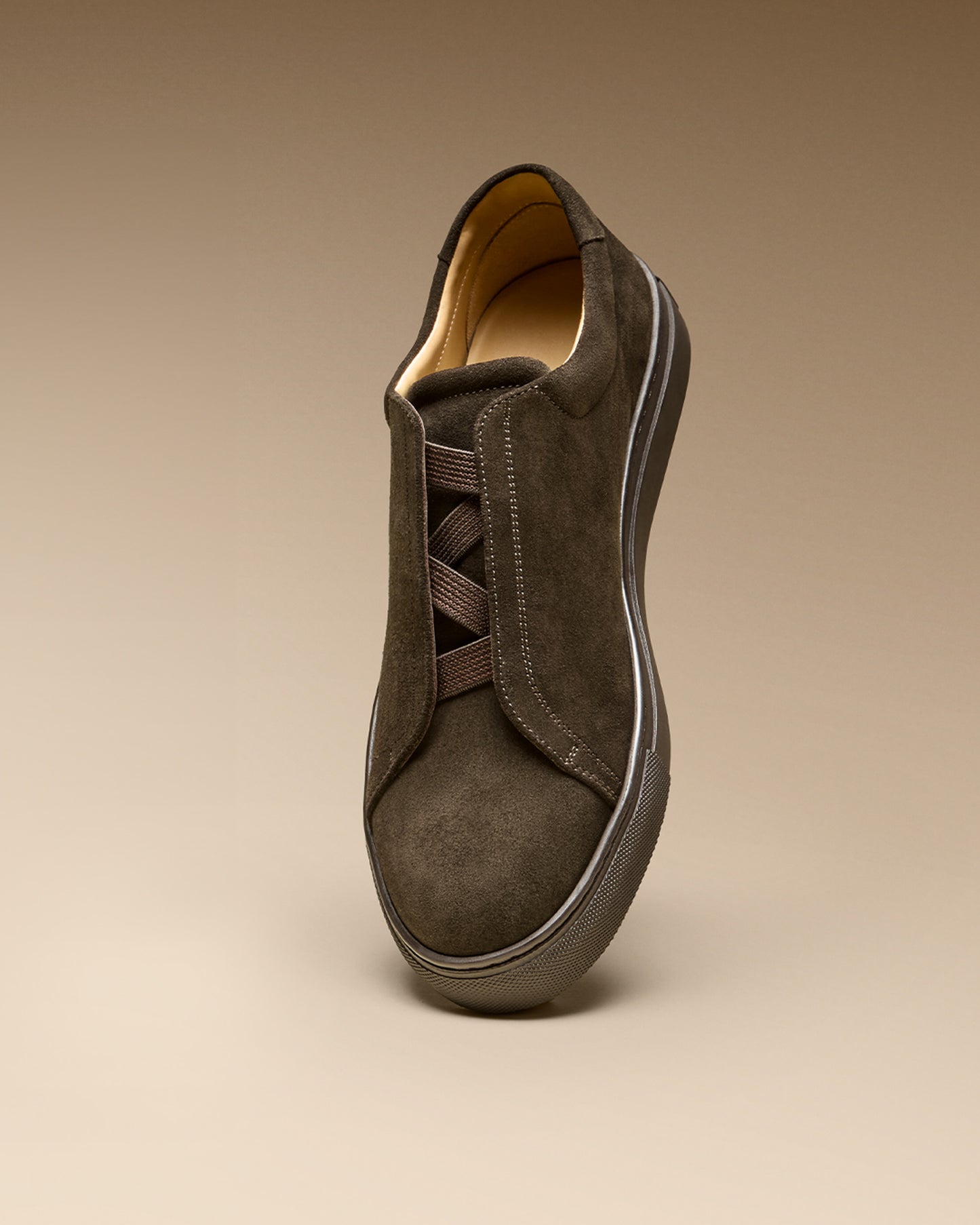 Studio shot of Alnö – Dark Brown Suede sneaker from a three-quarter angle, detailing its M-shaped elastic lacing.
