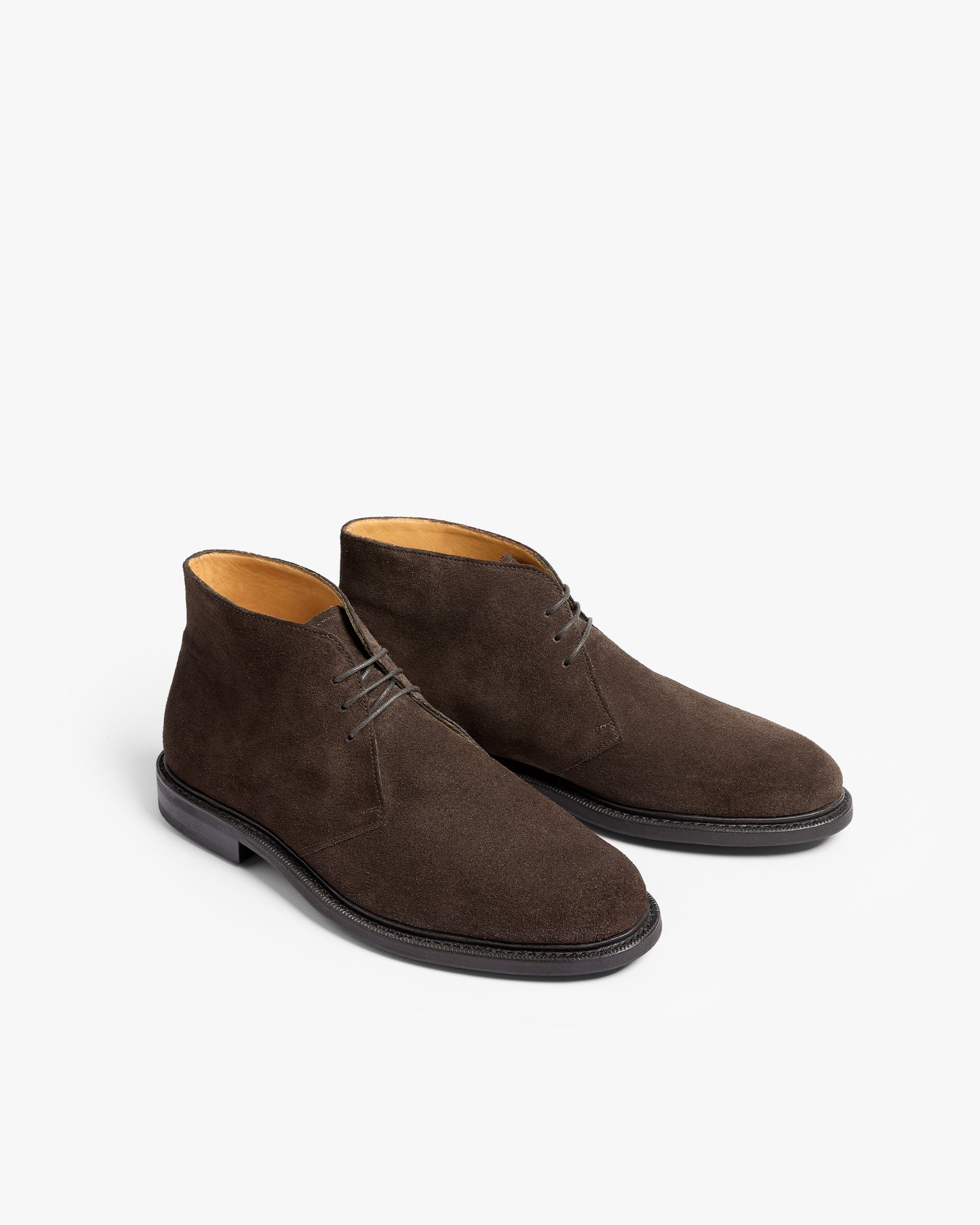 A pair of Gyllsjö II – Dark Brown Suede chukka boots with dark laces, shown at an angle against a white background.
