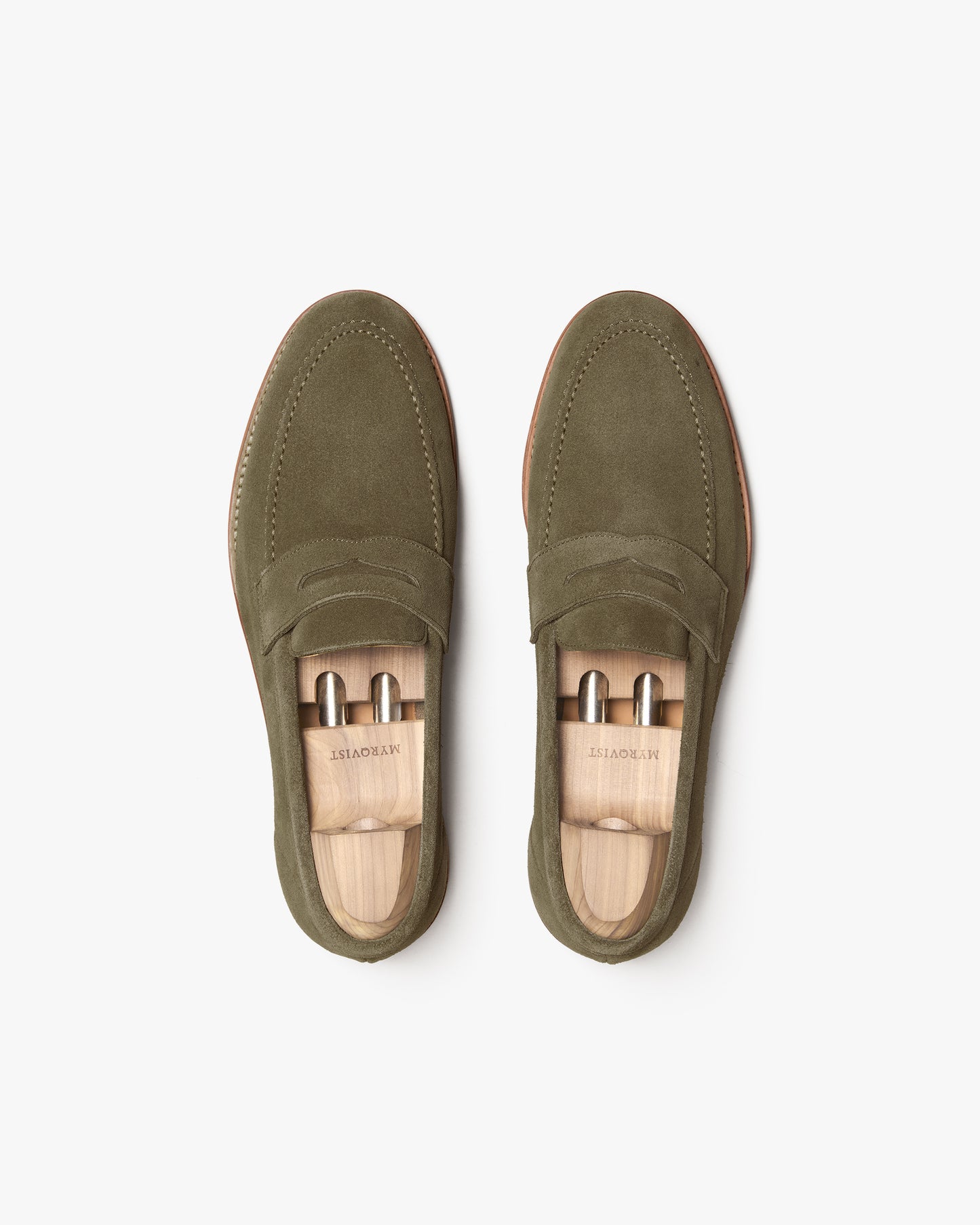 An overhead view of a pair of Lysekil II – Green Suede loafers with wooden shoe trees.