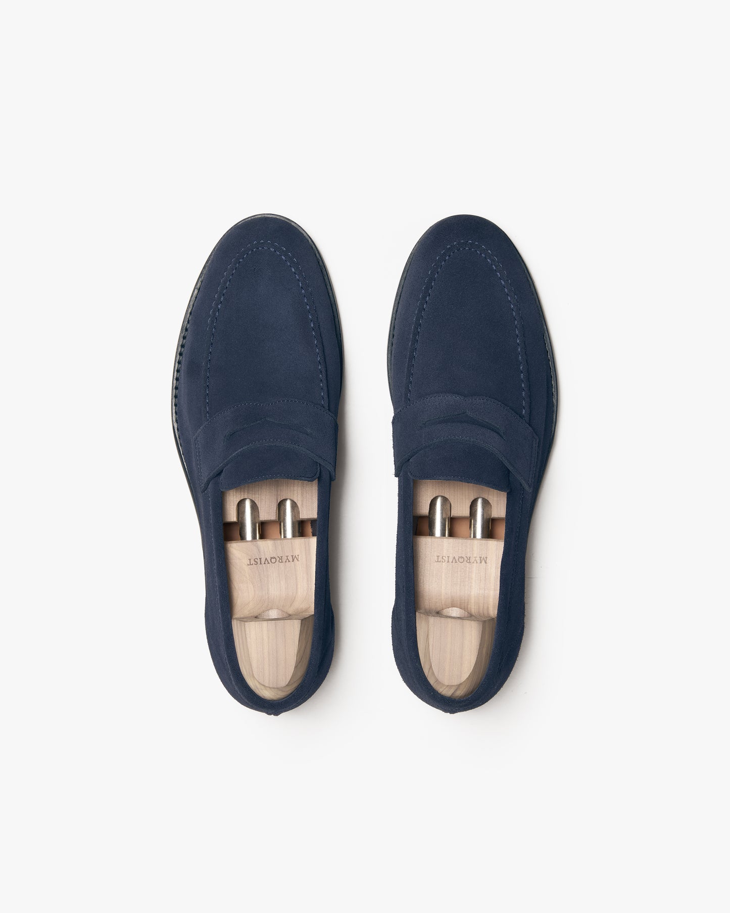 A pair of Lysekil II – Navy Suede loafers with shoe trees, shot from above on a white background.