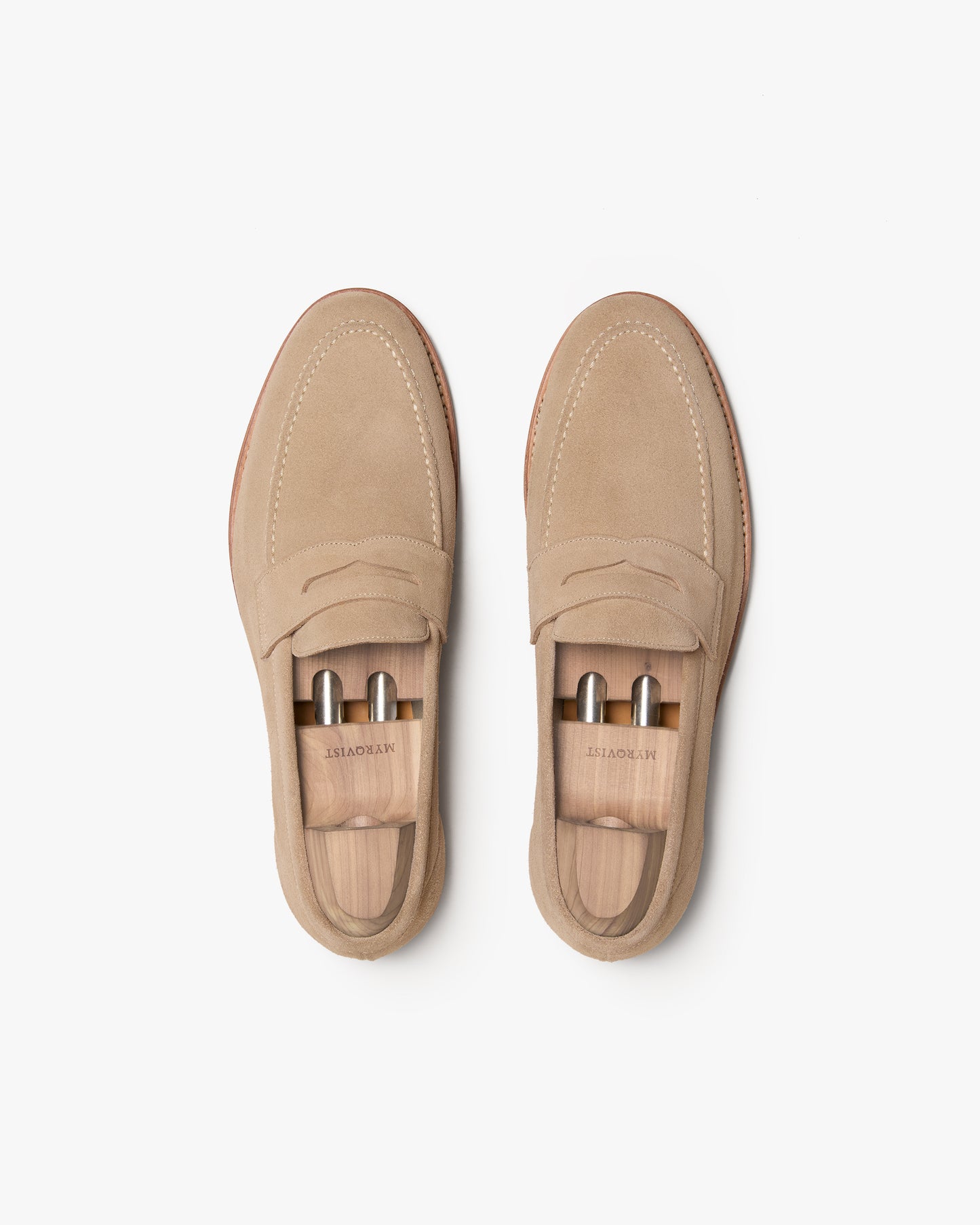 Top-down view of a pair of Lysekil II – Sand Suede loafers with wooden shoe trees against a white background.