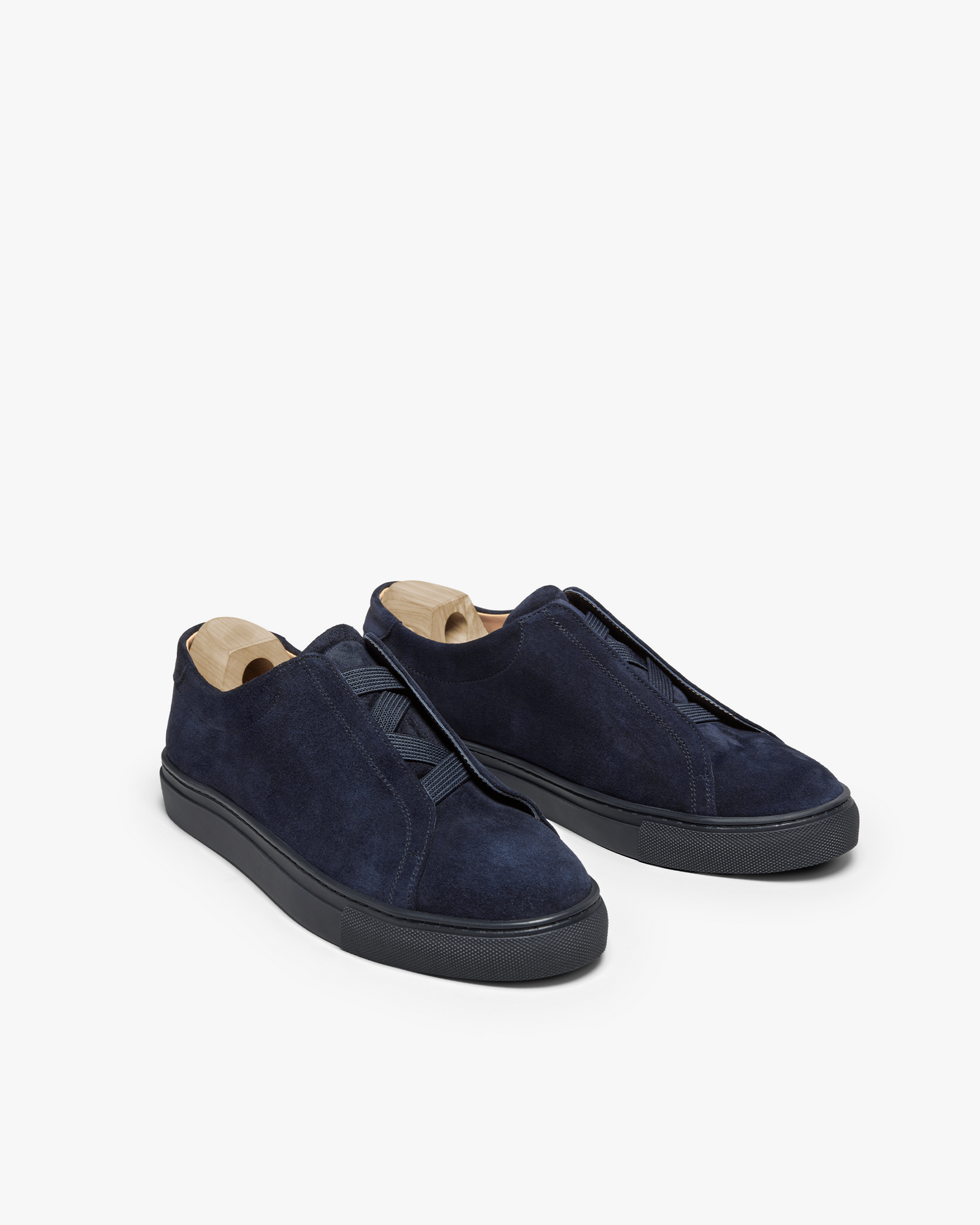 A pair of Alnö – Midnight Blue Suede sneakers with wooden shoe trees, pictured against a white background.