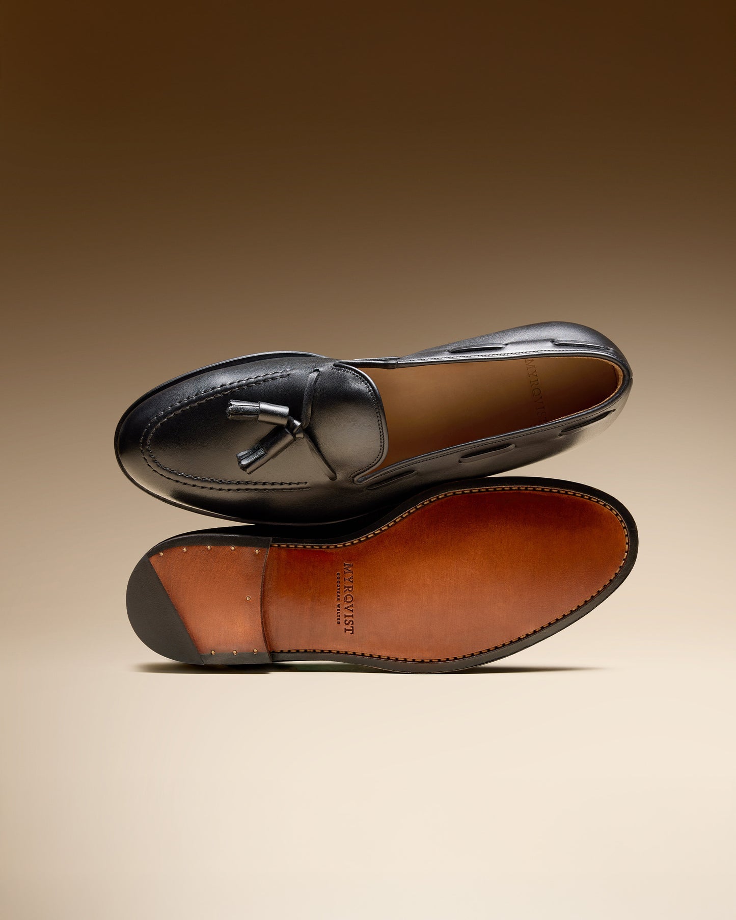 Mölle II – Black Calf tassel loafer resting on another to display the shoe's top view and its single leather sole.