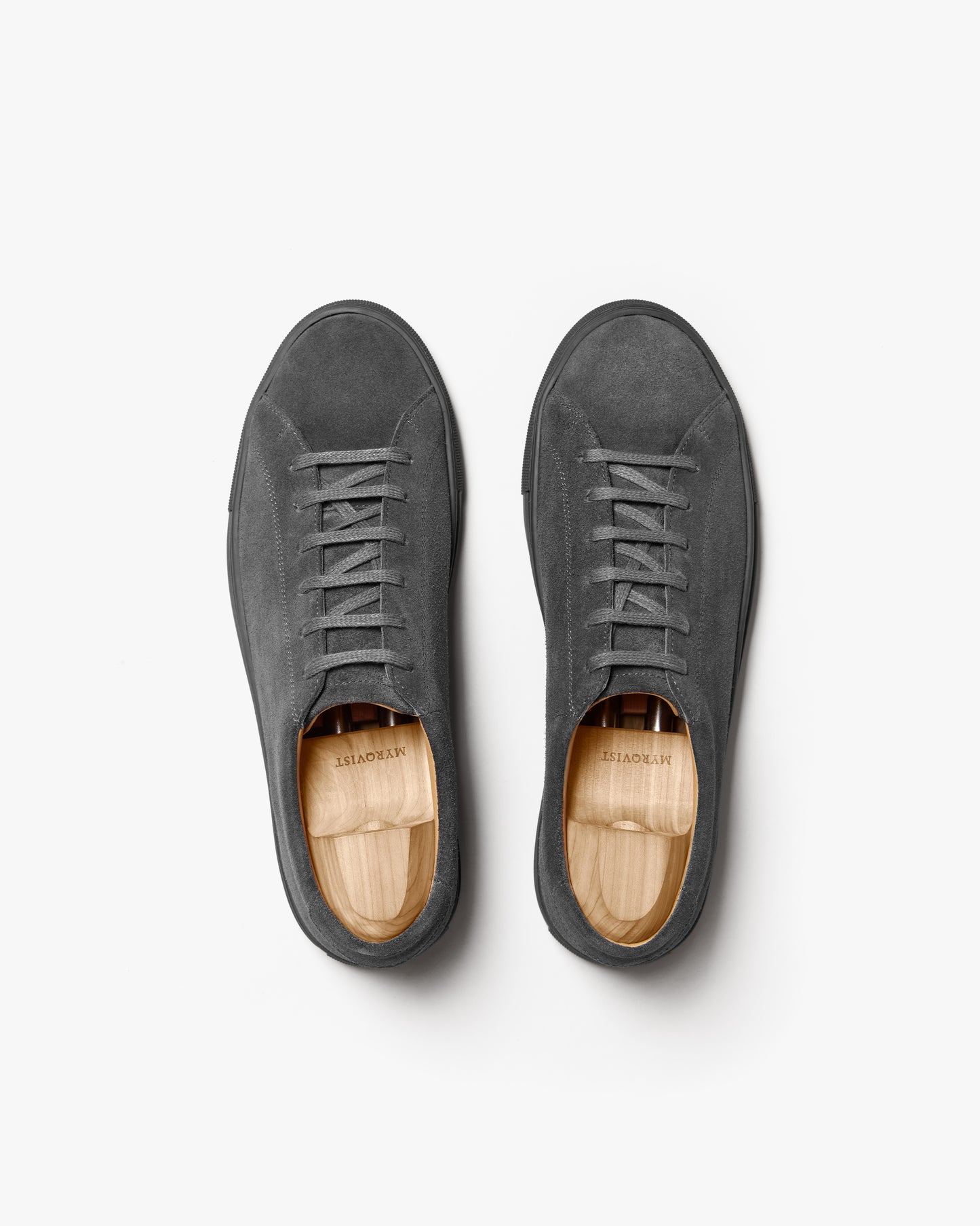 A pair of Oaxen Monochrome II – Dark Grey Suede sneakers with wooden shoe trees, shot from above against a white background.