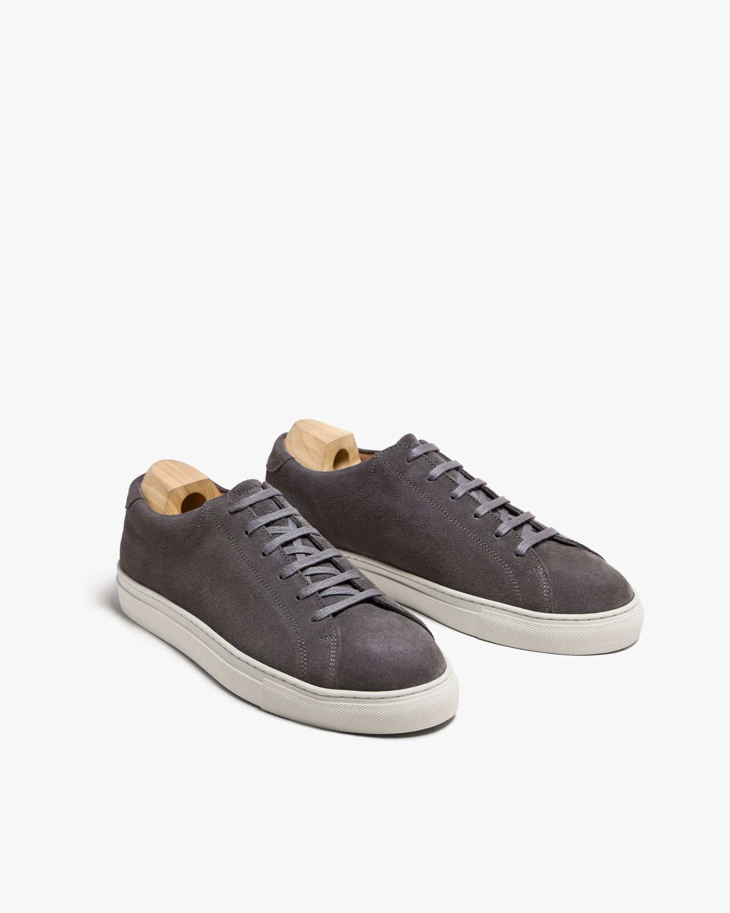 A pair of Oaxen II – Dark Grey Suede sneakers with wooden shoe trees, detailing the side profile and minimalist design.