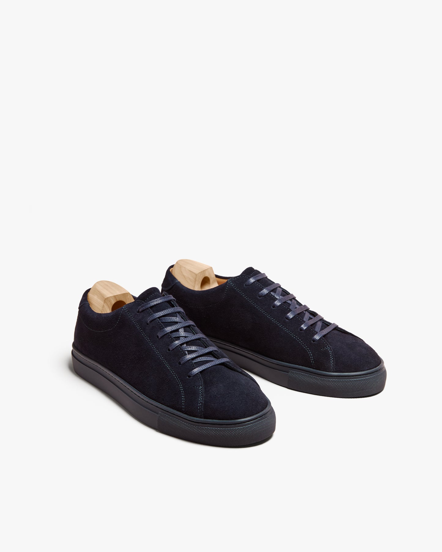 A pair of Oaxen Monochrome II – Navy Suede sneakers with wooden shoe trees, shown against a white background.