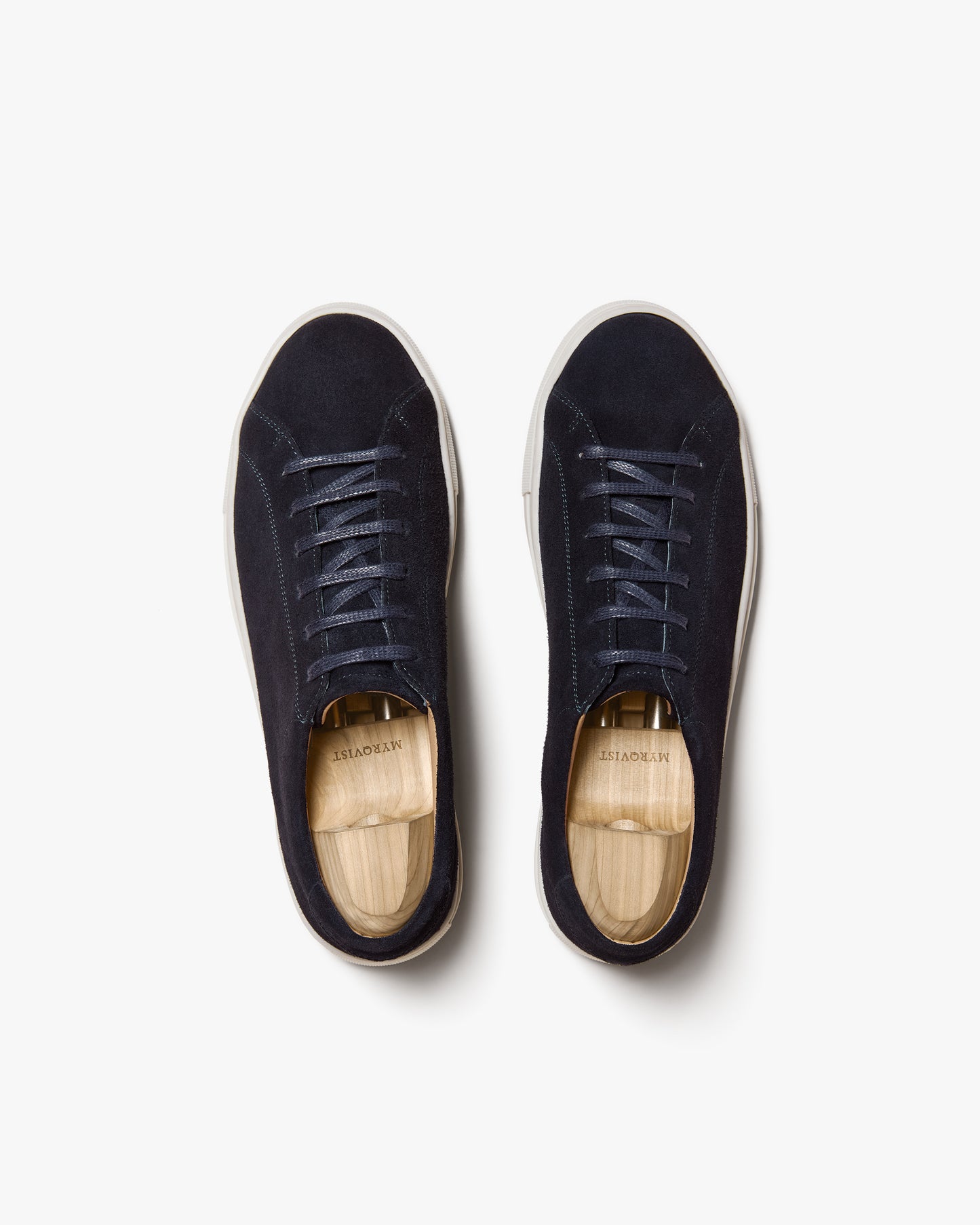 A top-down studio shot of Oaxen II – Navy Suede sneakers, fitted with wooden shoe trees.