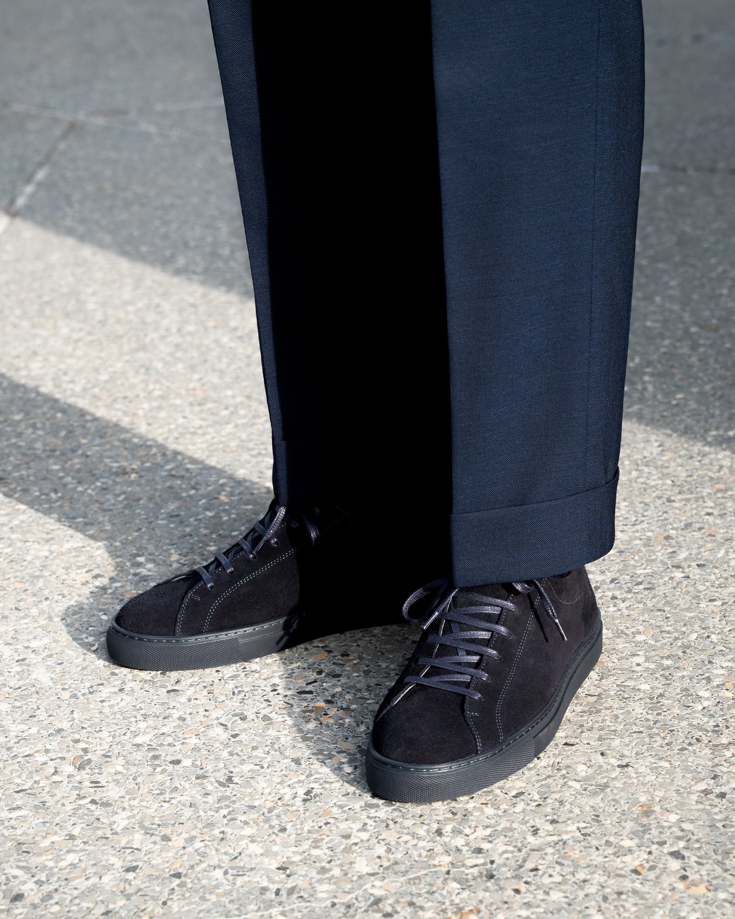 Close-up of a person wearing Oaxen Monochrome II – Navy Suede sneakers with cuffed navy trousers.