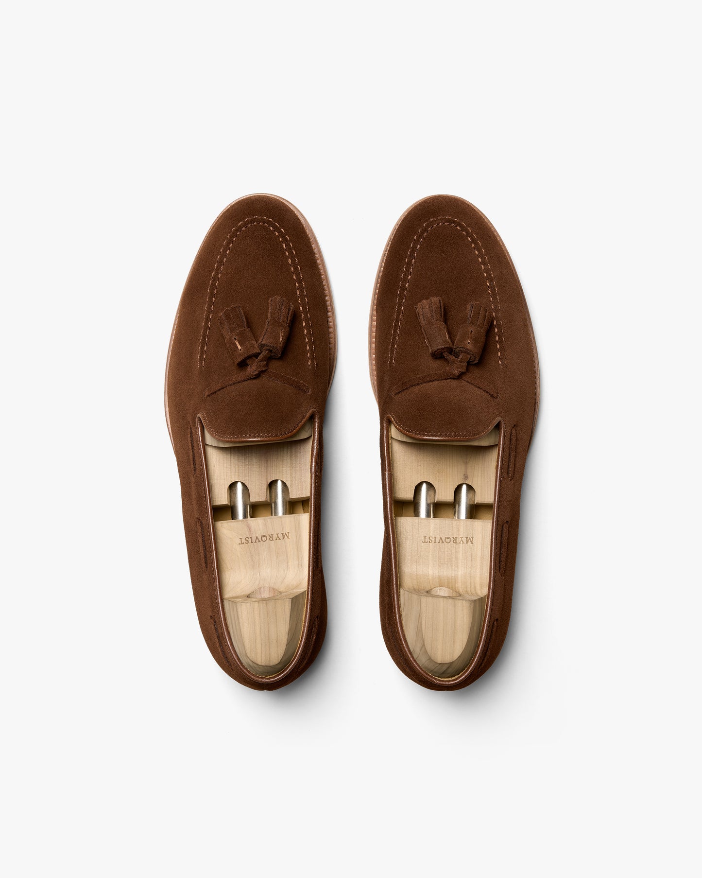 An overhead shot of a pair of Mölle II – Polo Suede loafers with wooden shoe trees on a white background.
