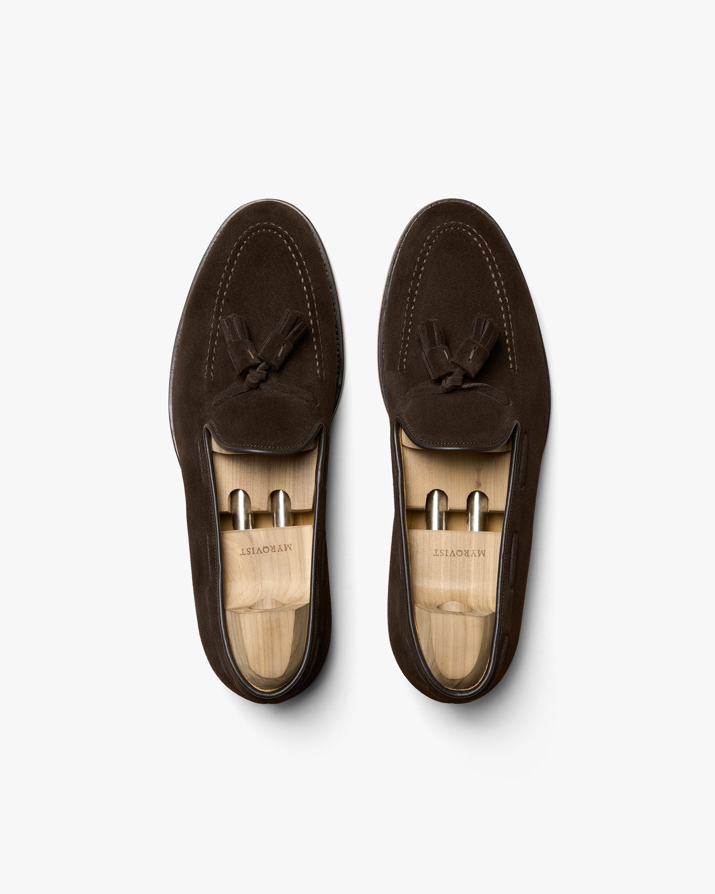 An overhead shot of Mölle II – Dark Brown Suede tassel loafers with shoe trees inside, against a white background.
