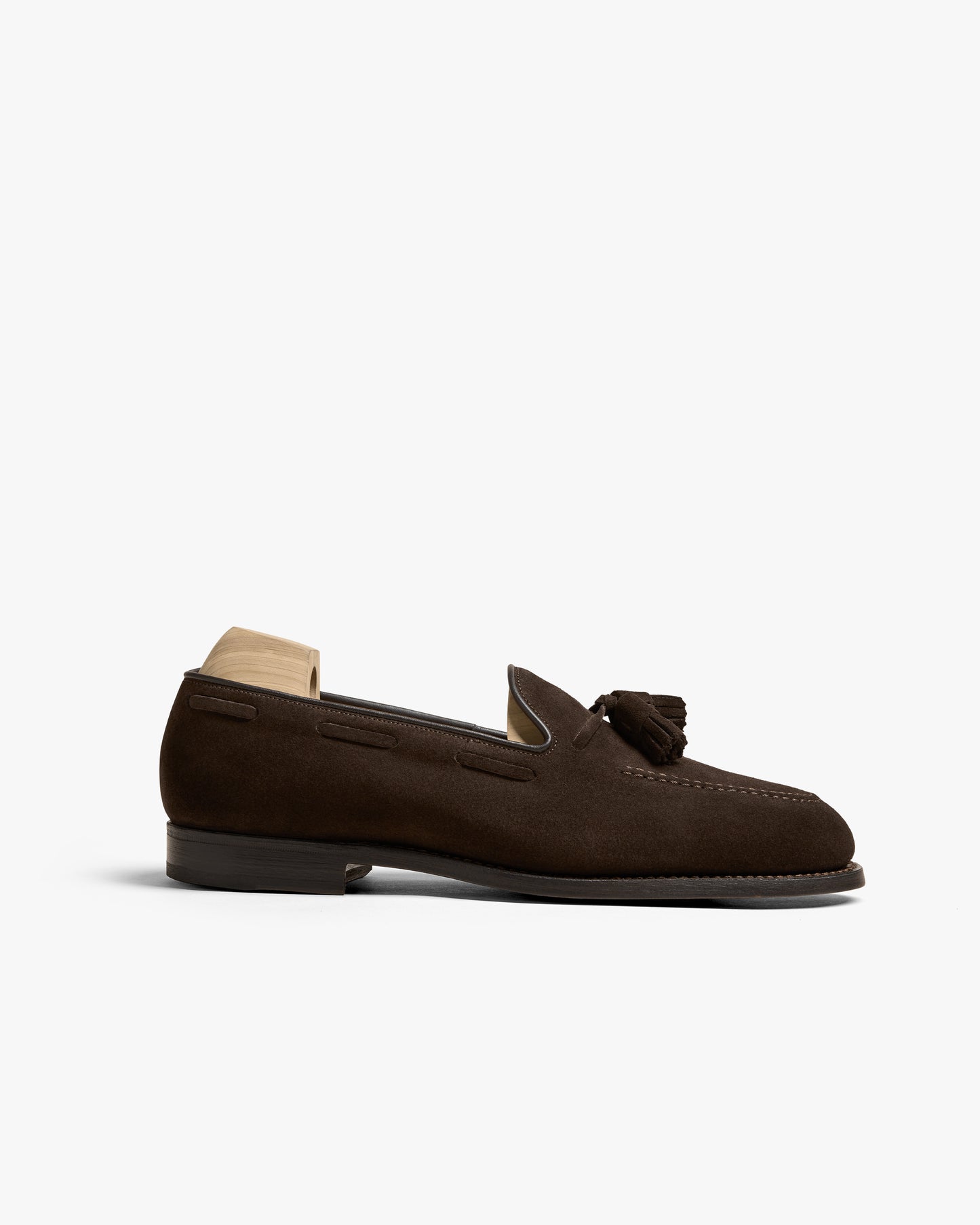 A side profile of the Mölle II – Dark Brown Suede loafer, highlighting its elegant silhouette and tassel detail.