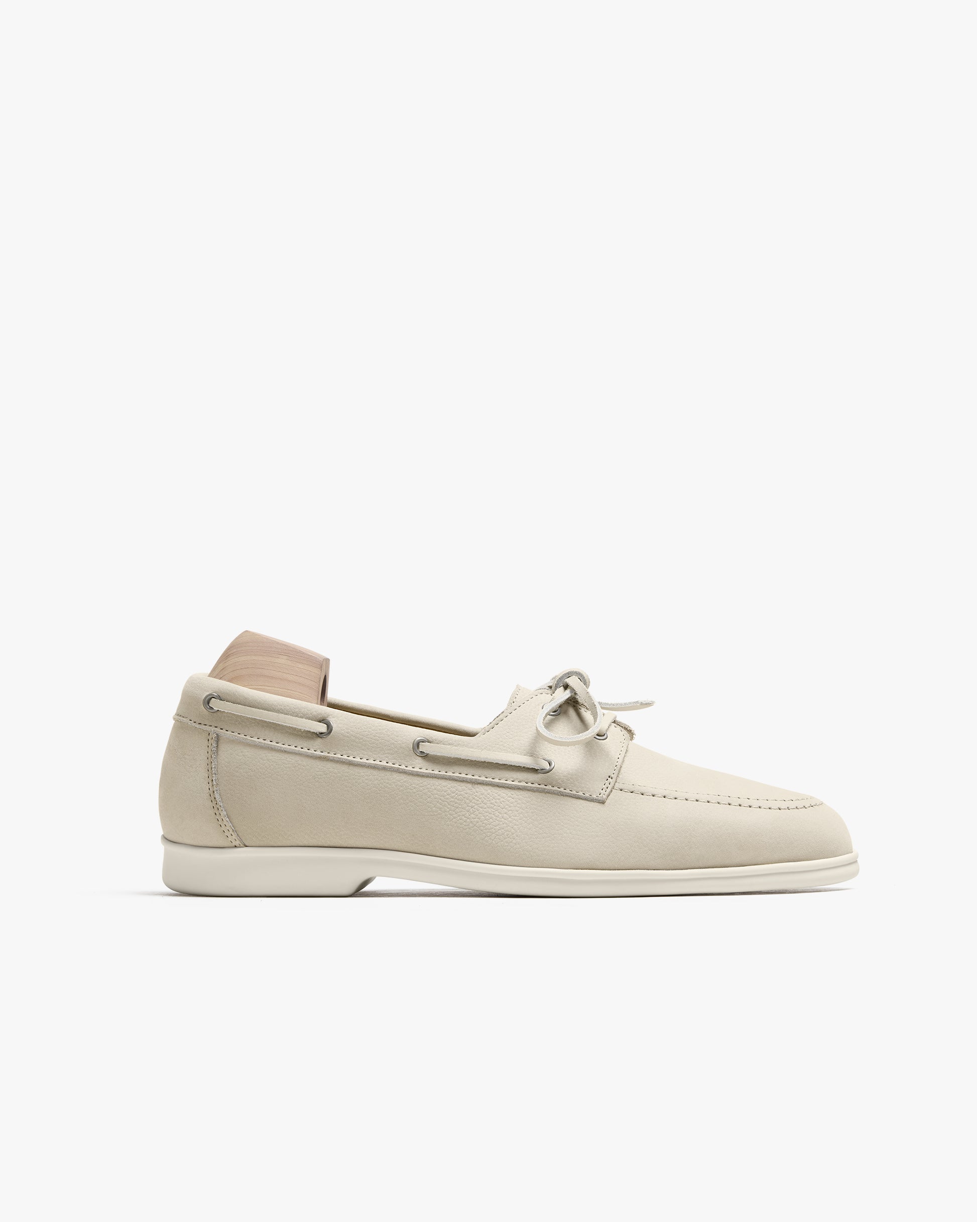 Side profile of Sandhamn – Beige Nubuck boat shoe with a wooden shoe tree, against a white background.