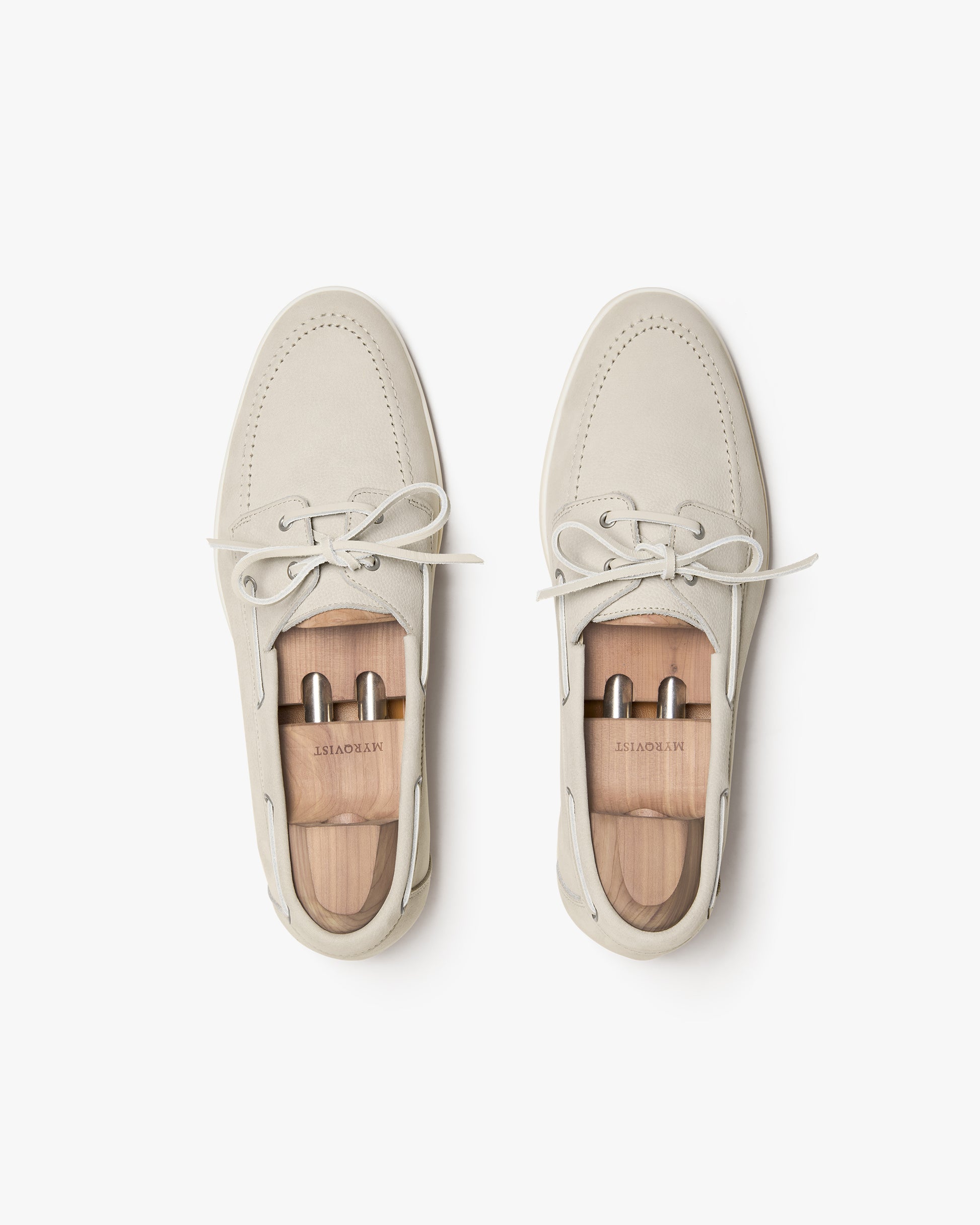 Top-down view of Sandhamn – Beige Nubuck boat shoes with wooden shoe trees on a white background.