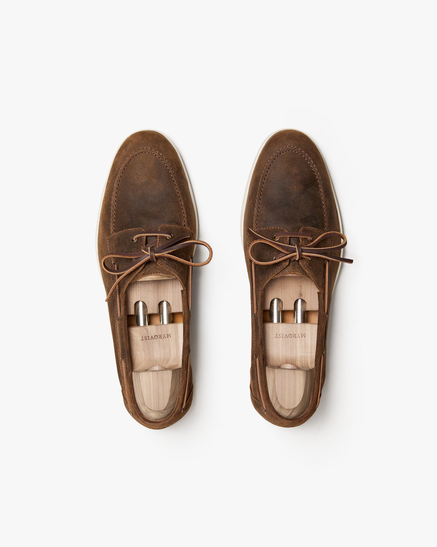 Top-down view of a pair of Sandhamn – Chestnut Waxed Suede boat shoes with wooden shoe trees inside.