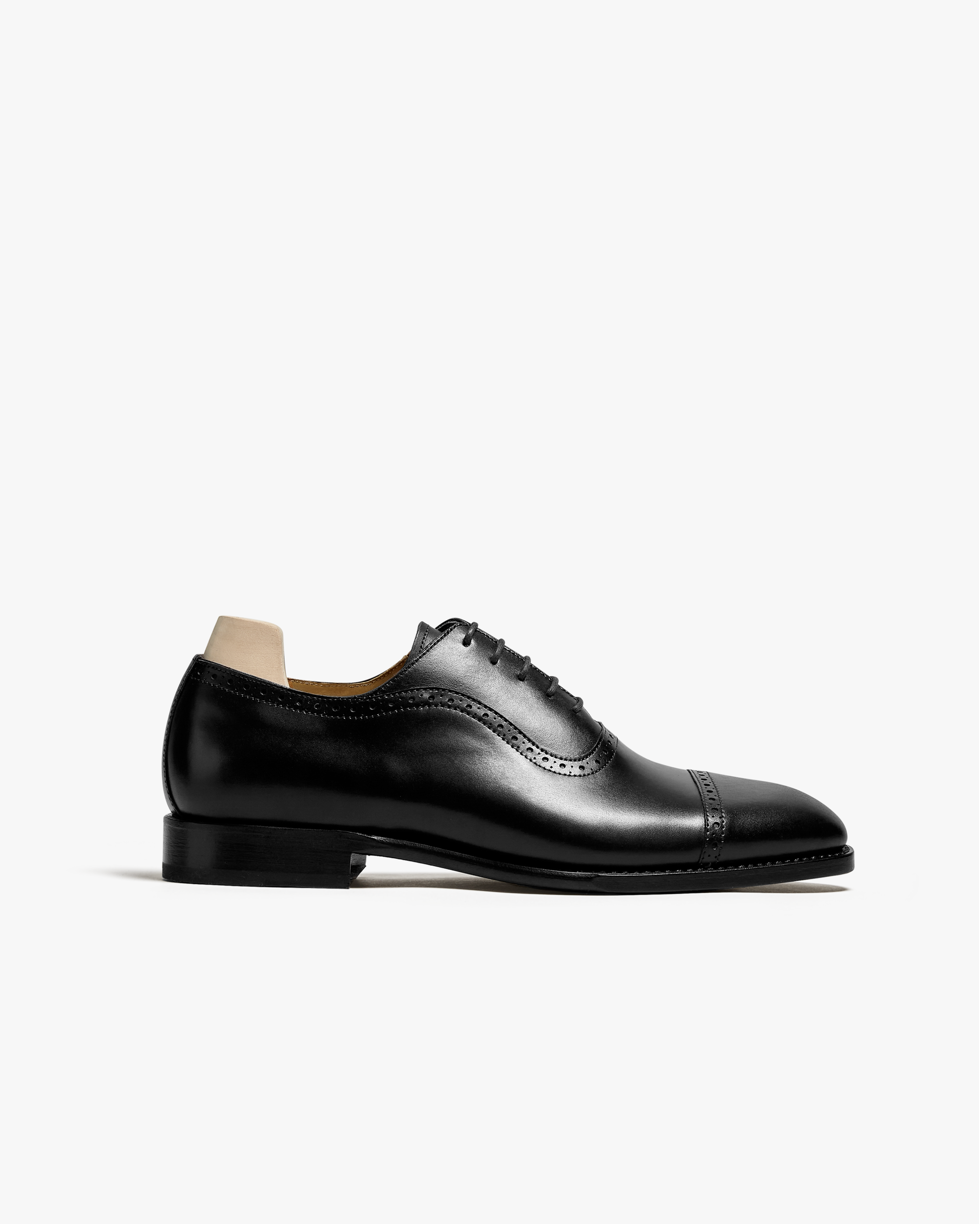 A side profile view of Skytteholm – Black Calf, a black leather quarter brogue oxford, shown against a white background.