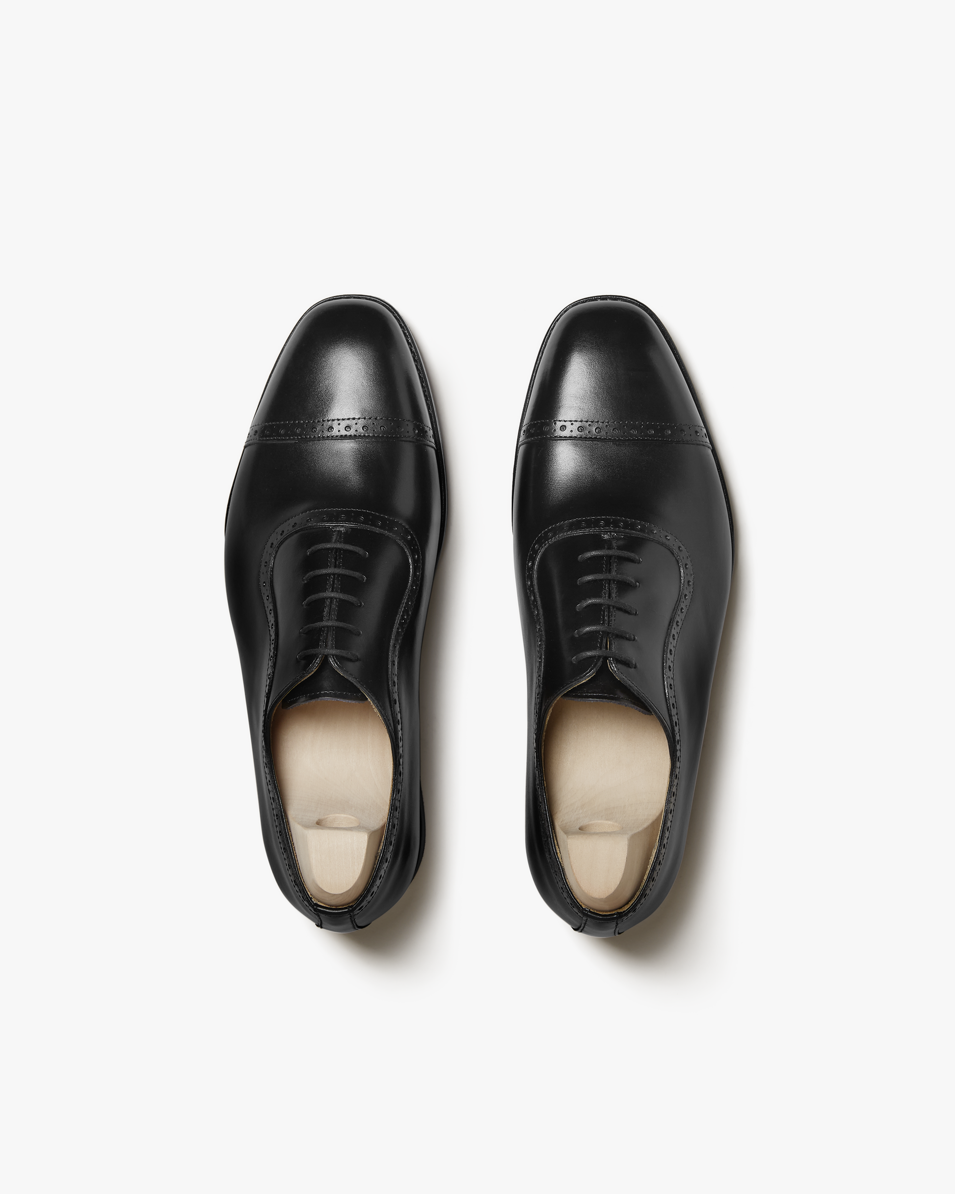 A pair of Skytteholm – Black Calf Oxford shoes with wooden shoe trees, photographed from above on a white background.