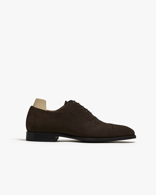A side profile of Skytteholm – Dark Brown Suede, an elegant quarter brogue oxford shoe, on a white background.