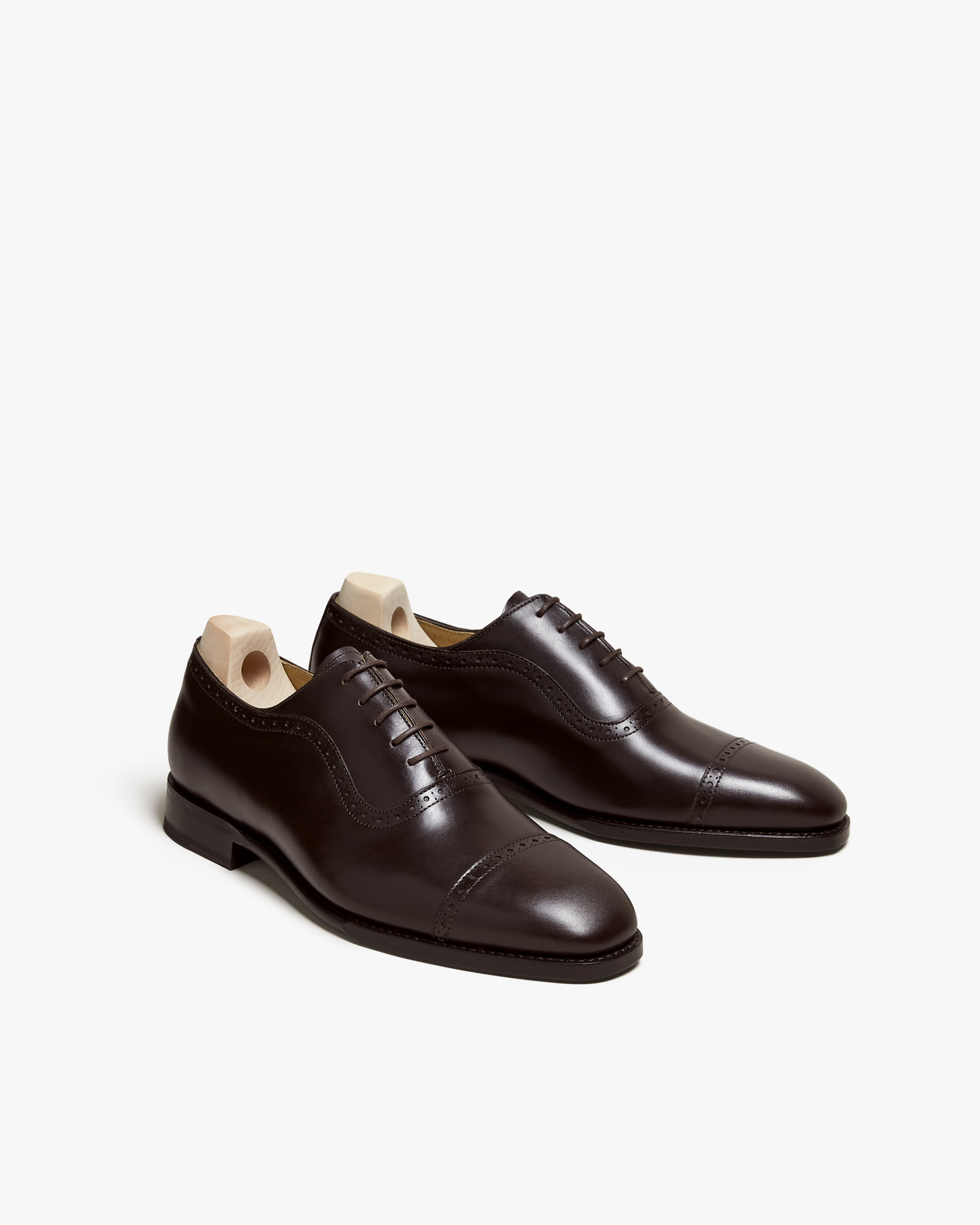 A pair of Skytteholm – Dark Brown Calf oxford shoes with shoe trees, angled against a white background.