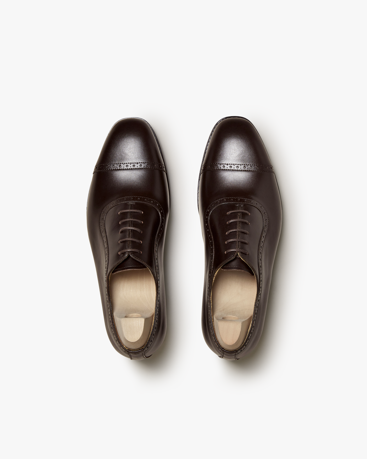 Top-down view of Skytteholm – Dark Brown Calf oxford shoes, displayed as a pair with shoe trees on a white surface.