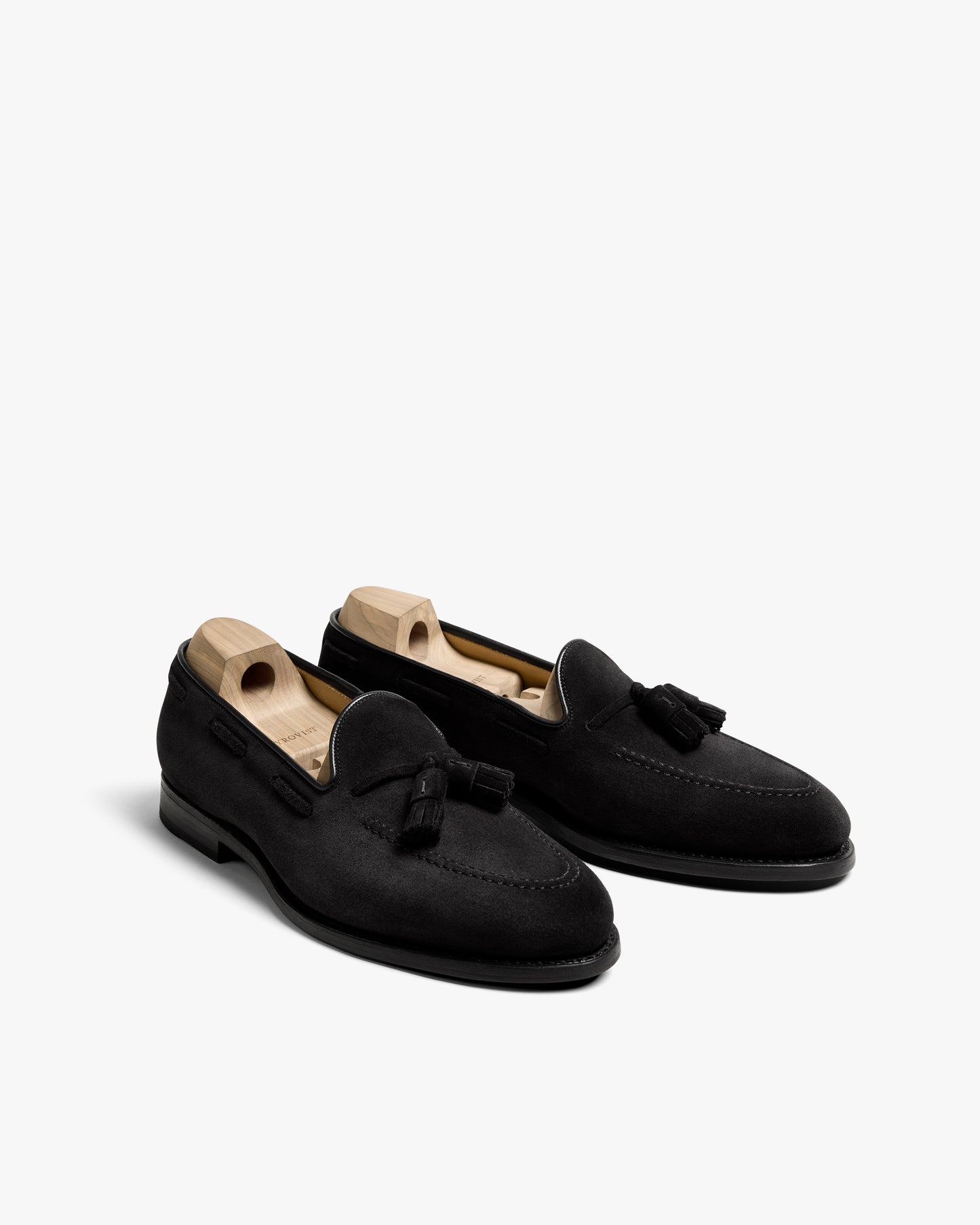 A pair of Mölle II – Black Suede tassel loafers shown from a three-quarter angle against a white background.