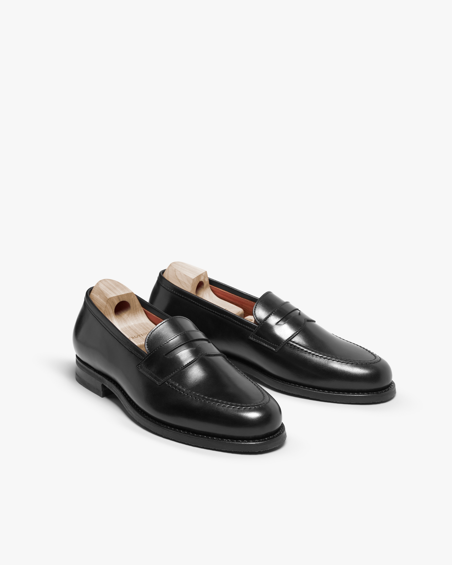 A pair of Stenhammar II – Black Calf penny loafers with wooden shoe trees, shot against a plain white background.