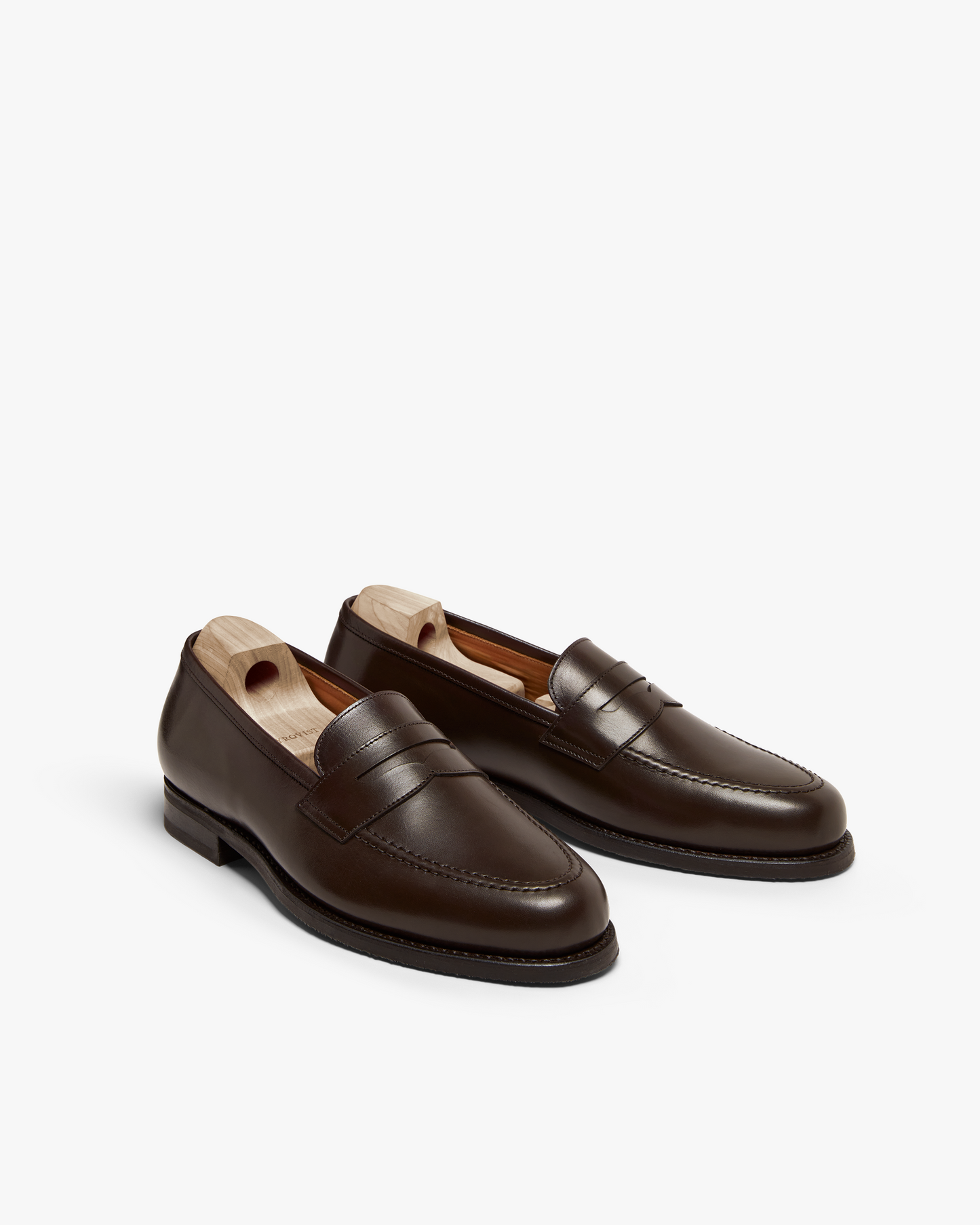 A pair of Stenhammar II – Dark Brown Calf penny loafers with wooden shoe trees, shown against a white background.