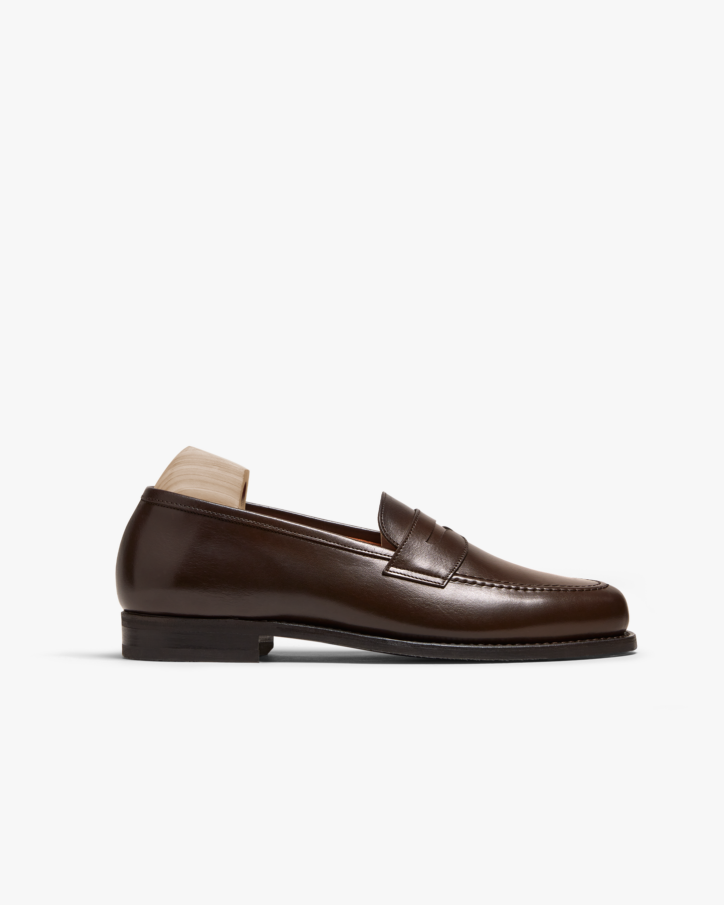 Side profile of Stenhammar II – Dark Brown Calf, a penny loafer with a wooden shoe tree against a white background.