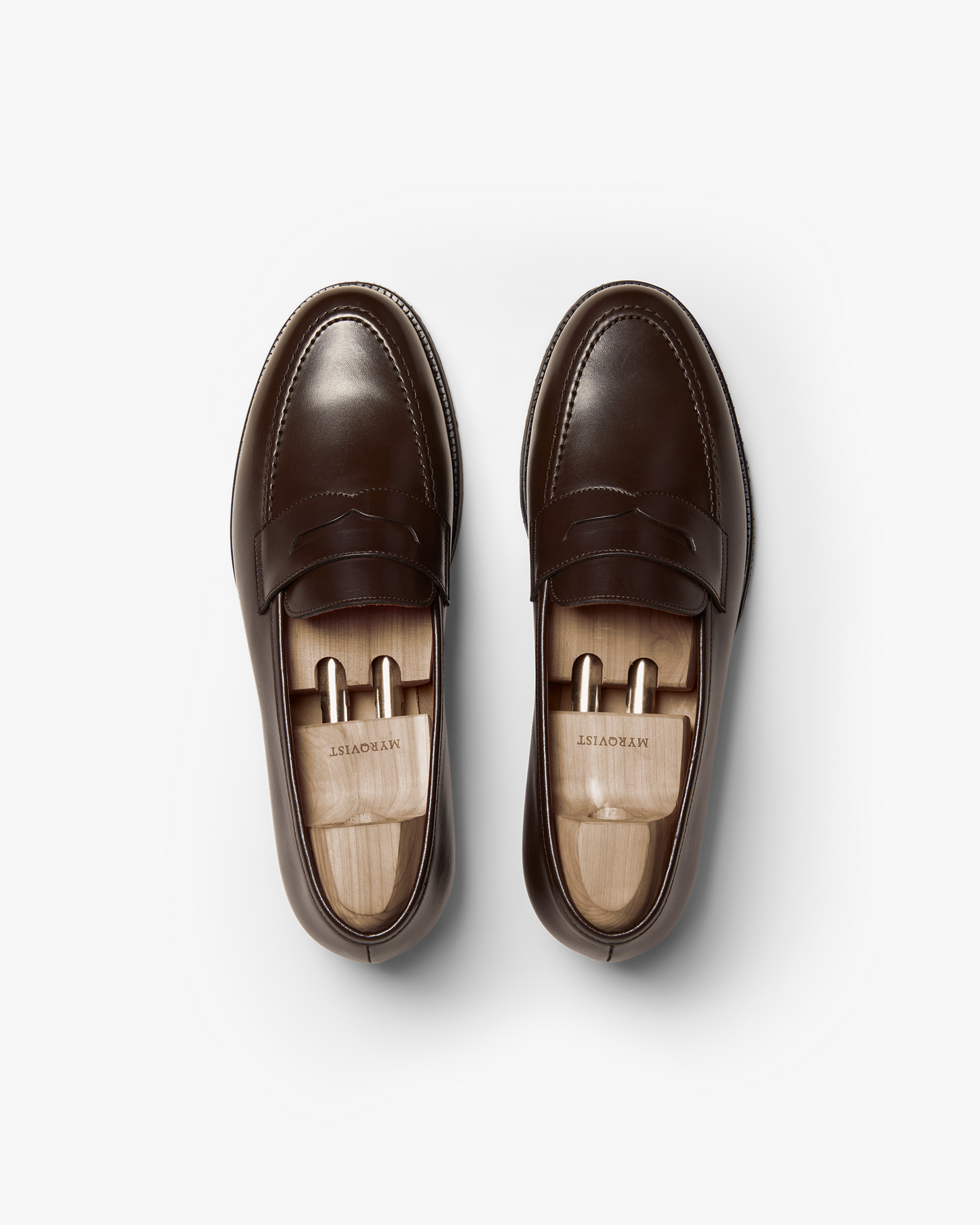A top-down view of Stenhammar II – Dark Brown Calf penny loafers, fitted with wooden shoe trees on a white background.