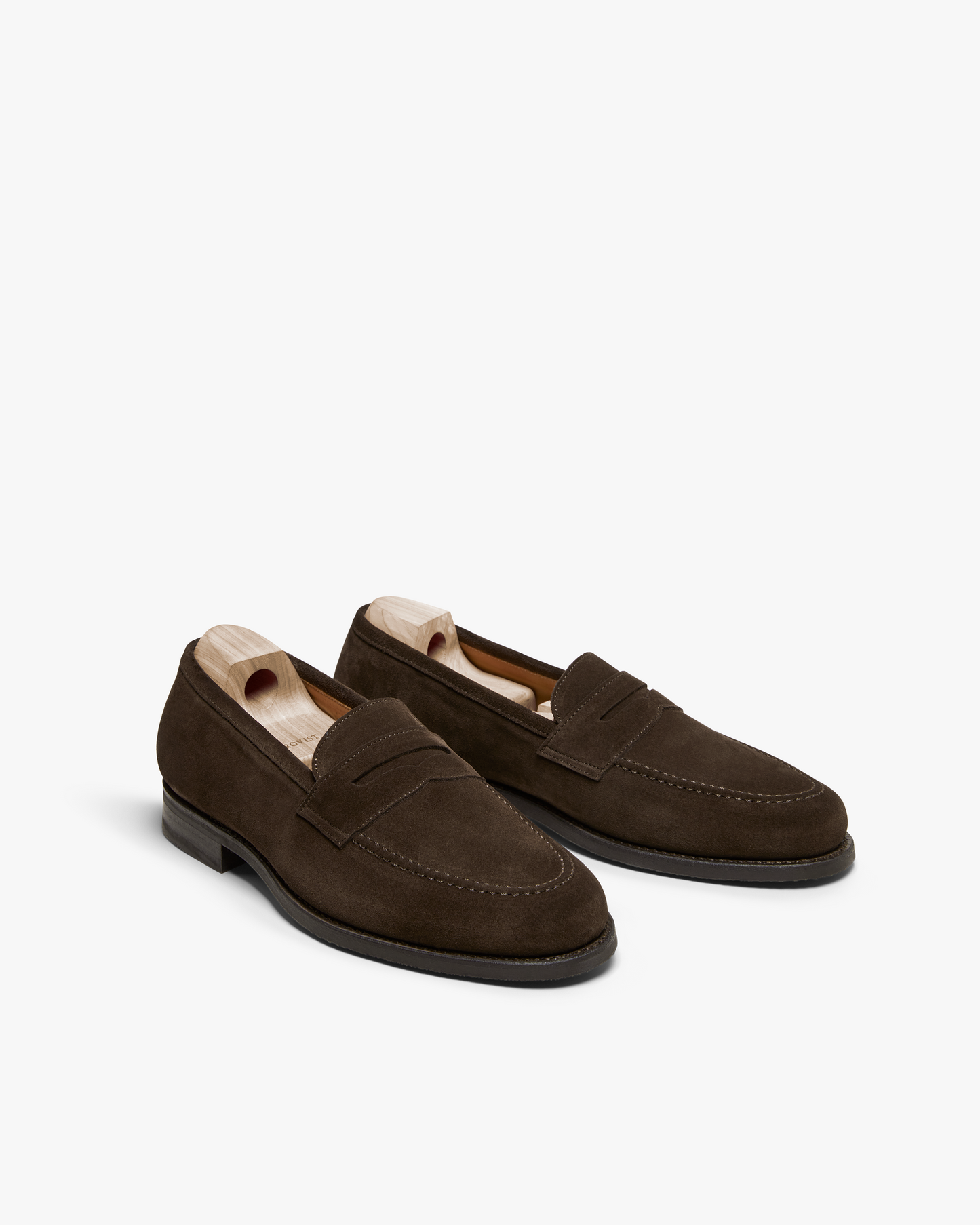 A pair of Stenhammar II – Dark Brown Suede penny loafers with wooden shoe trees, pictured against a white background.