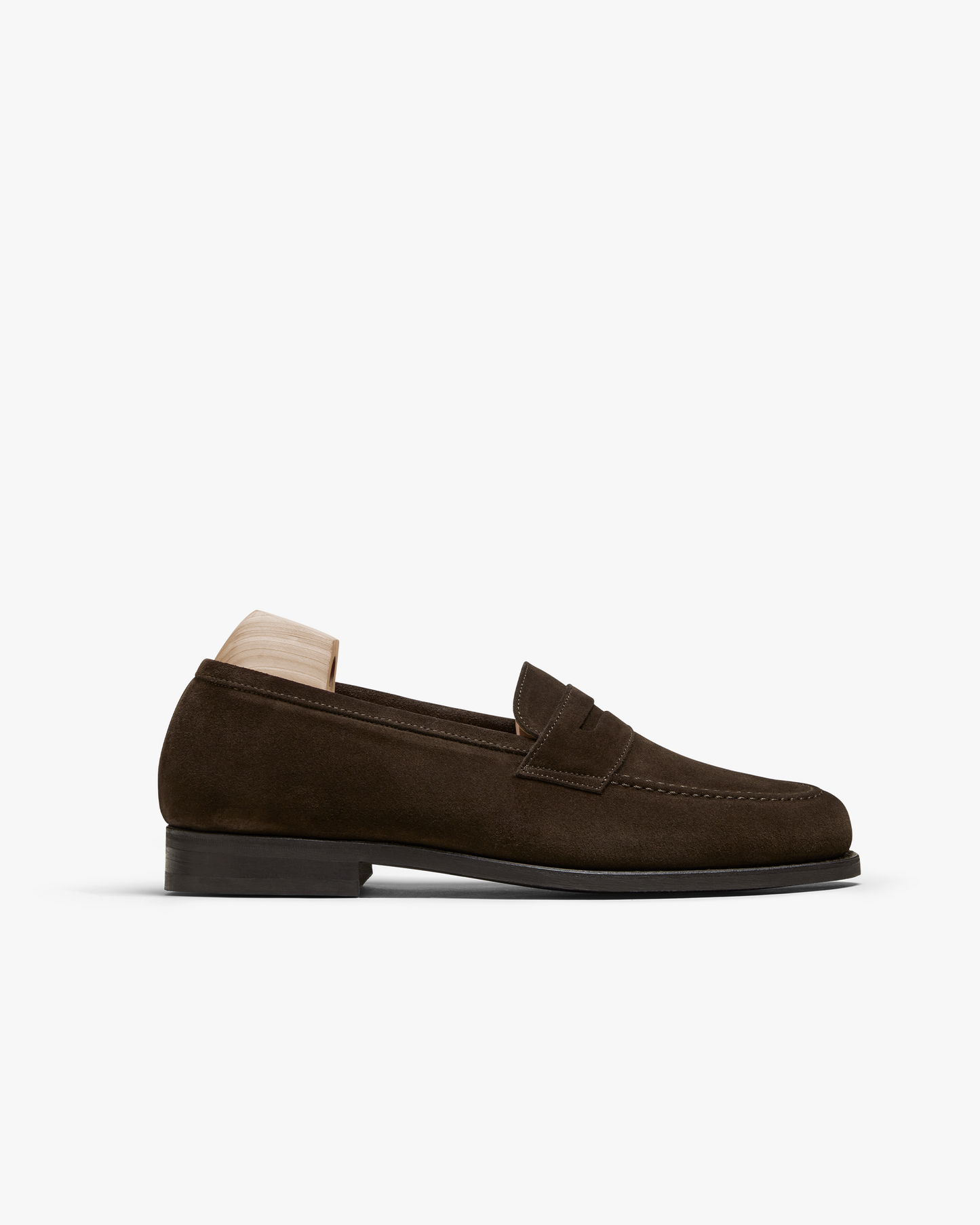 A close-up of the Stenhammar II – Dark Brown Suede loafer, showing its side profile with a wooden shoe tree inside.