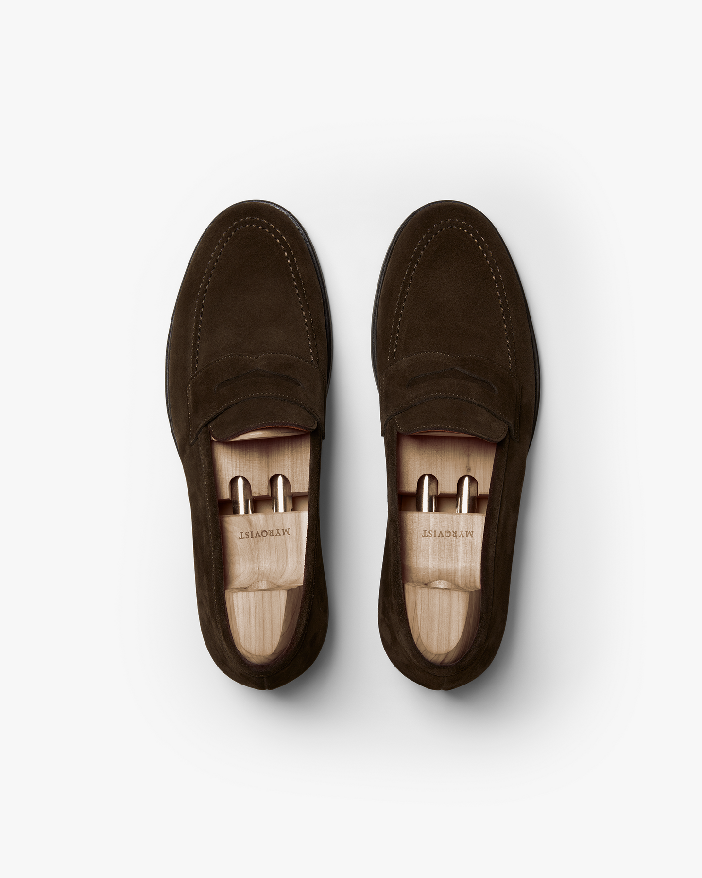 A top-down studio photograph of Stenhammar II – Dark Brown Suede loafers, fitted with wooden shoe trees.