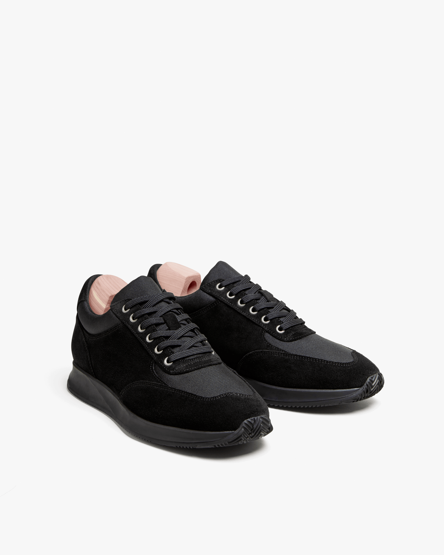 Studio shot of the Stensund – Black Suede trainers, angled to showcase the black suede and breathable mesh panels.