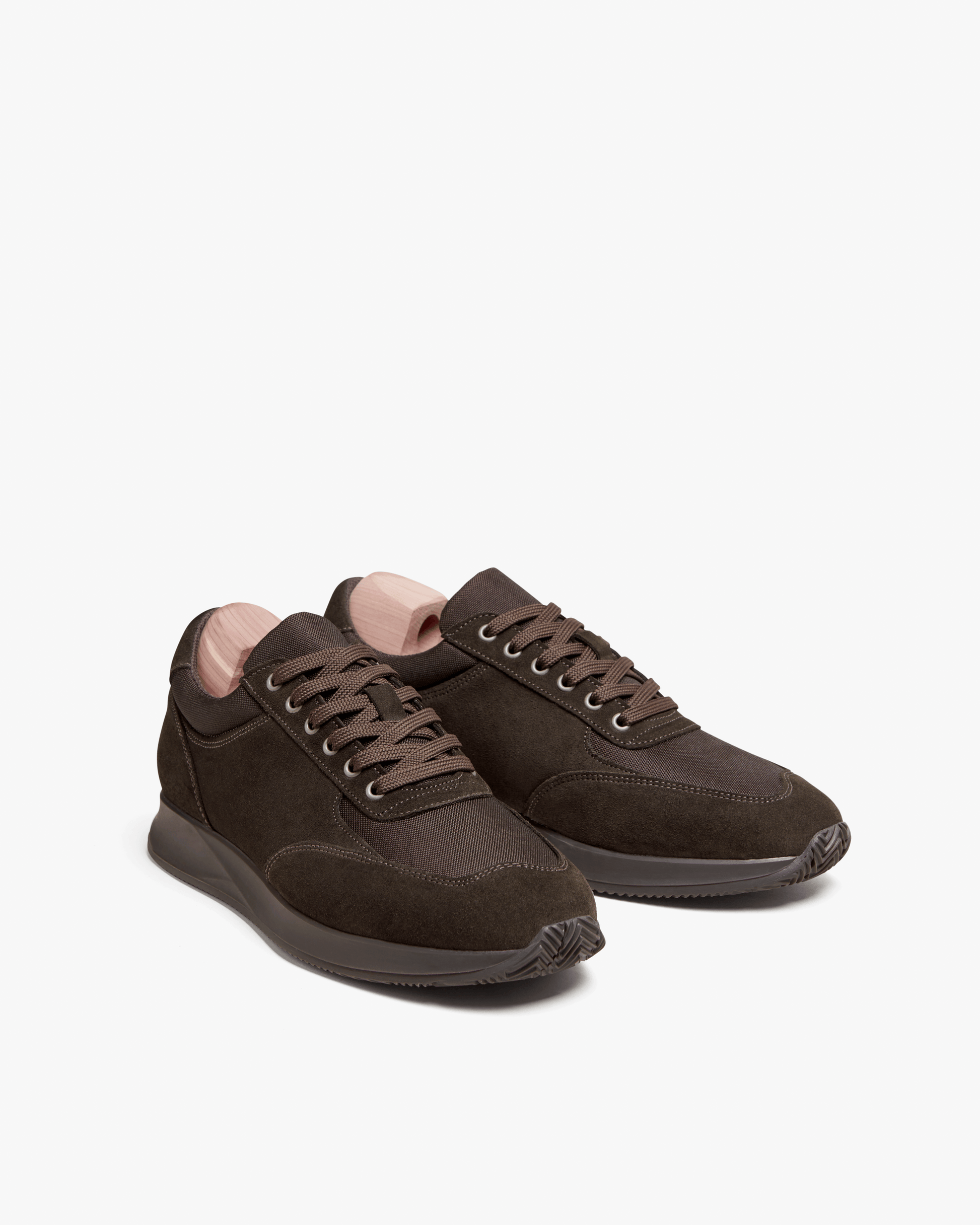 A pair of Stensund – Dark Brown Suede sneakers with shoe trees inside, shown against a white background.
