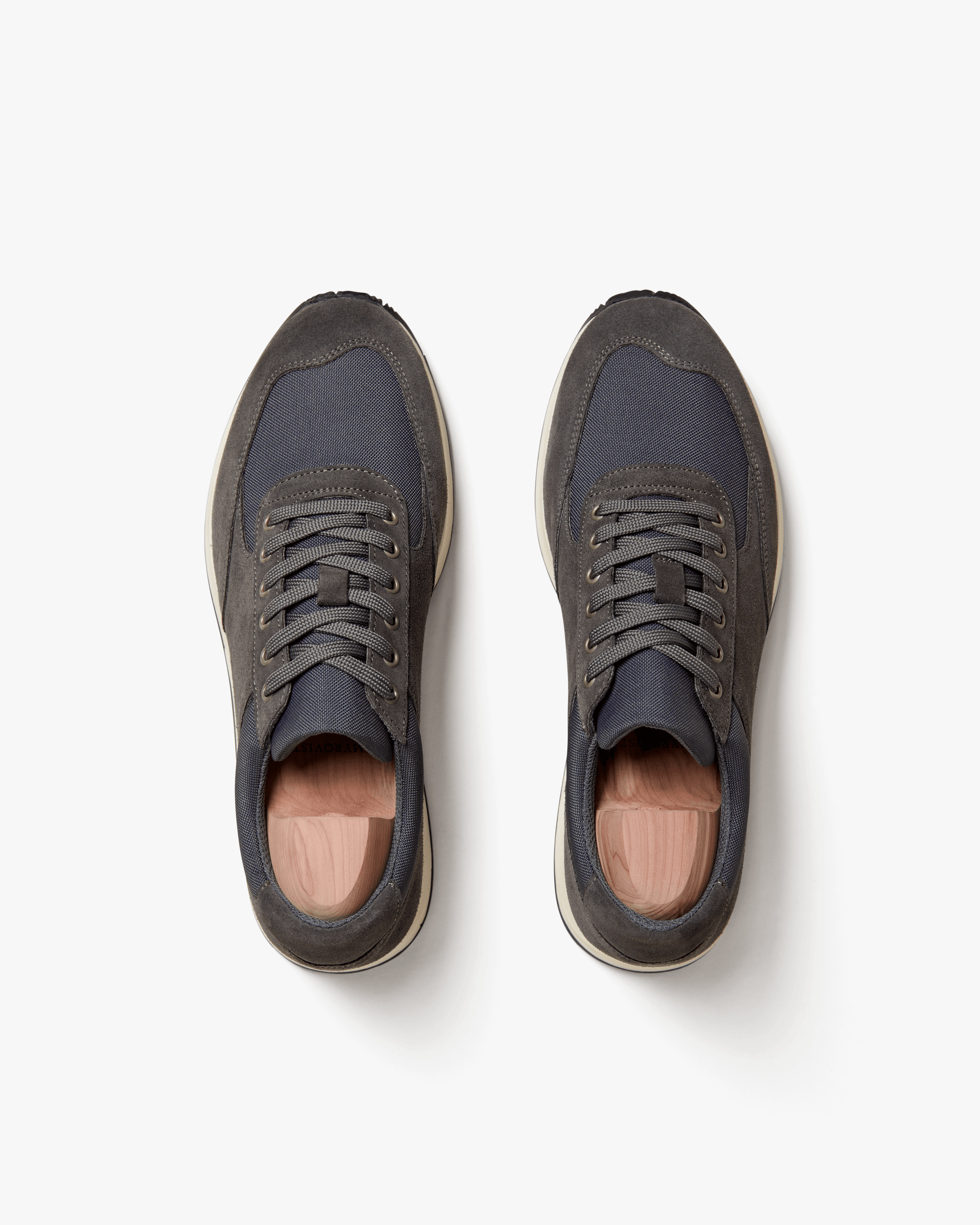 A pair of Stensund – Dark Grey Suede sneakers fitted with shoe trees, photographed from above on a white background.