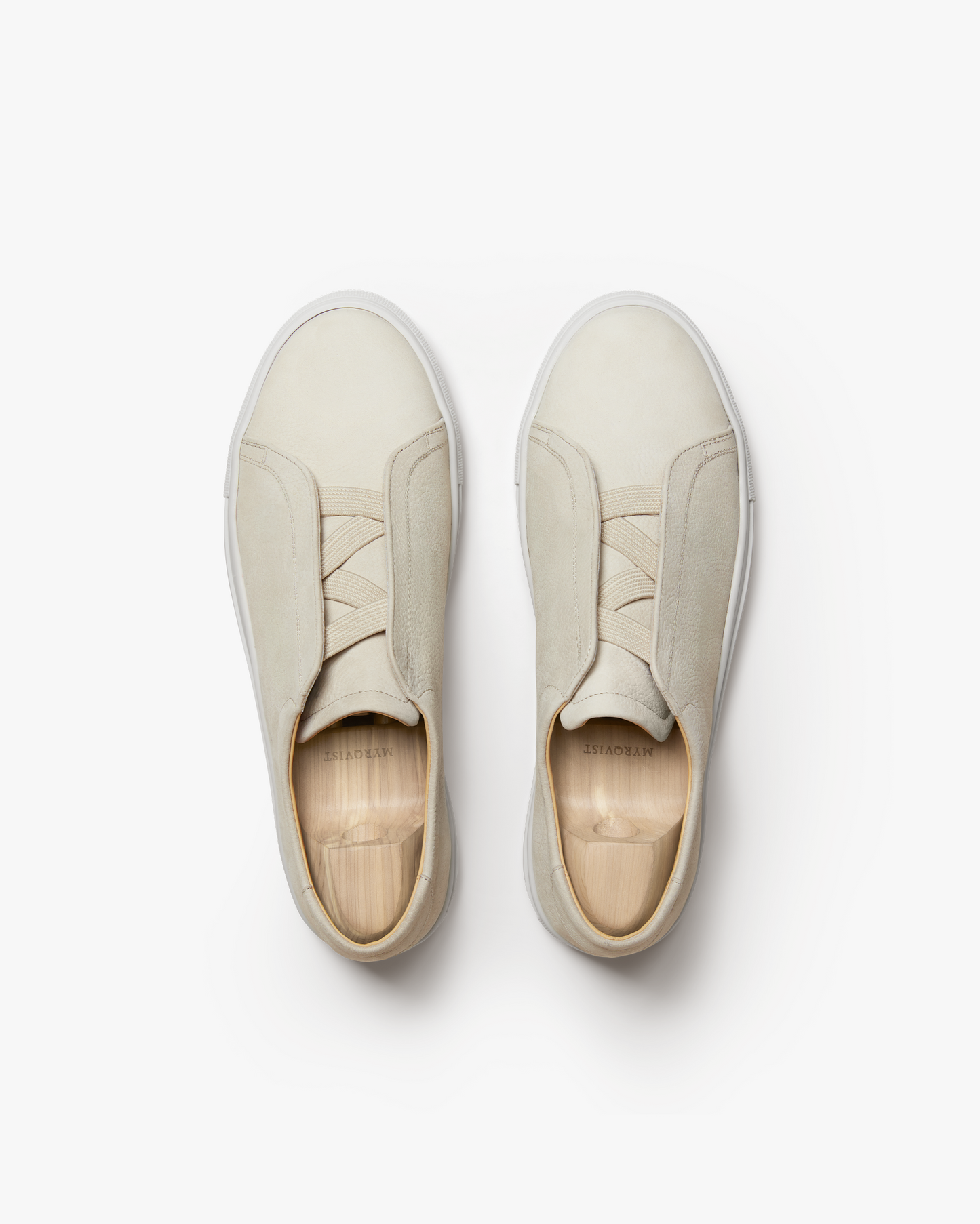 A top-down view of Alnö – Beige Nubuck sneakers, presented with wooden shoe trees against a white background.